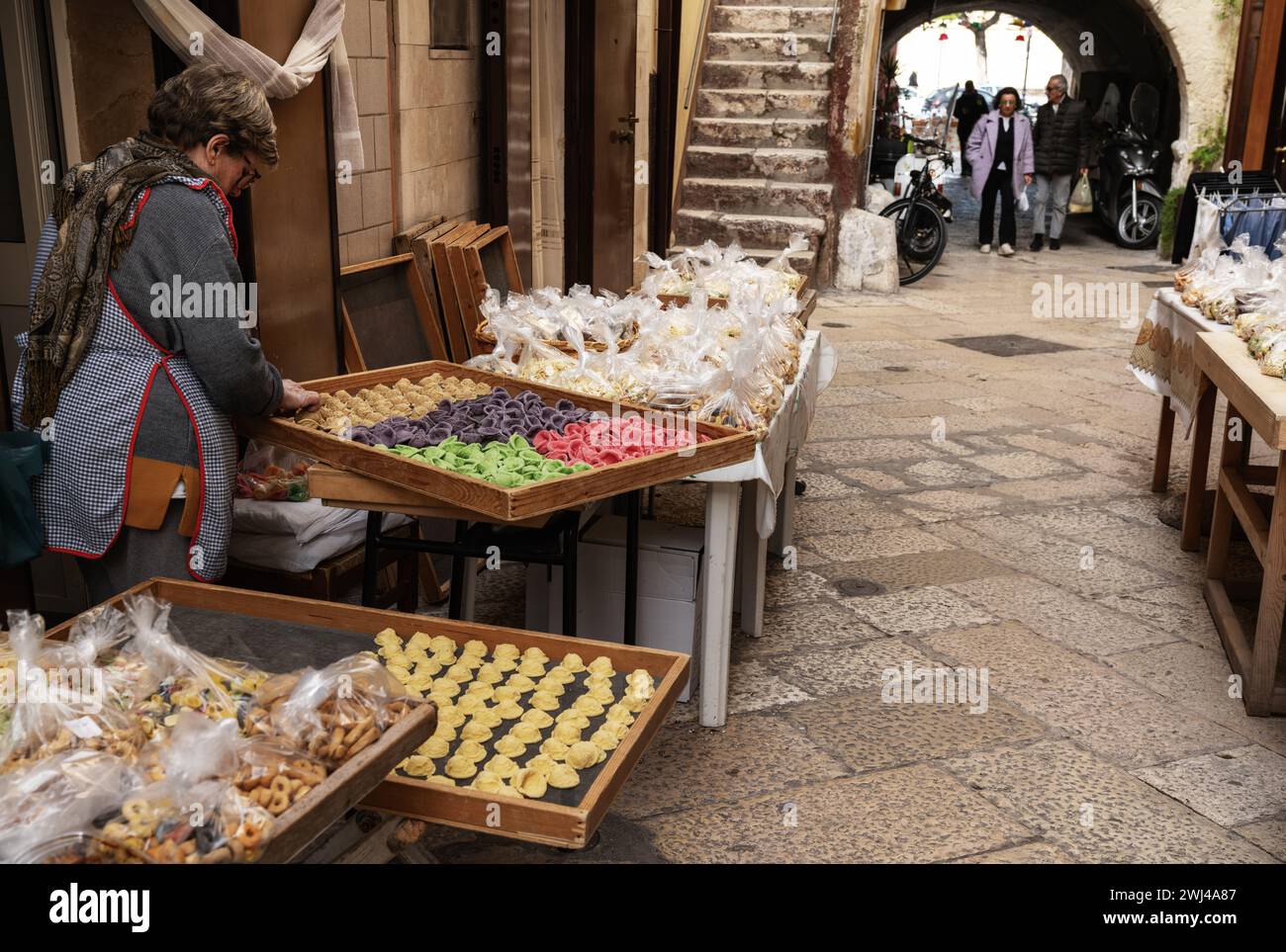 Woman pasta maker laying out her wares in the iconic Strada del Orecchiette in the old town of Bari Vecchio Stock Photo