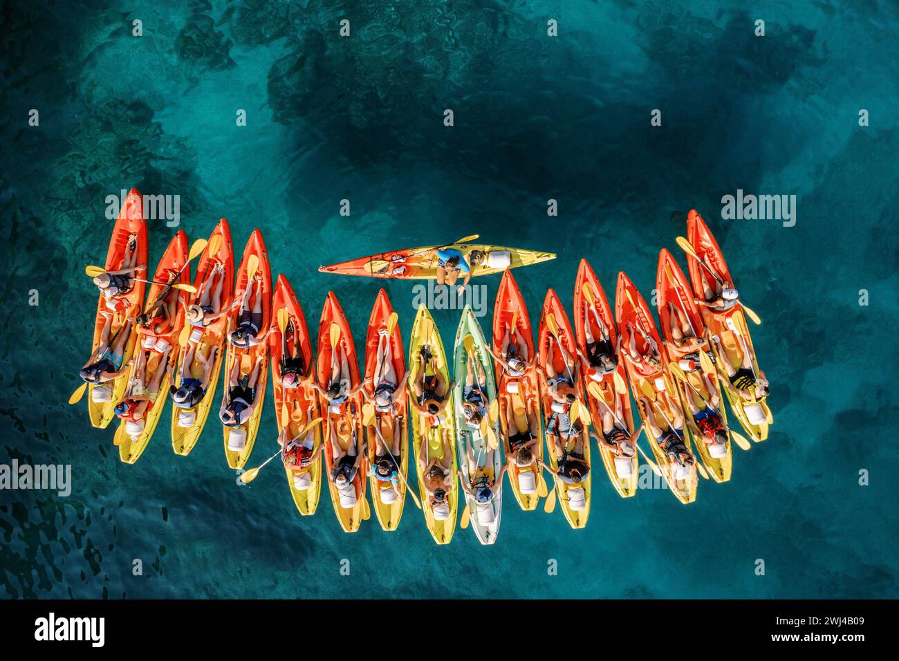 Captain of the kayaking team stands perpendicular in the boat in front of a row of kayaks. Top view Stock Photo