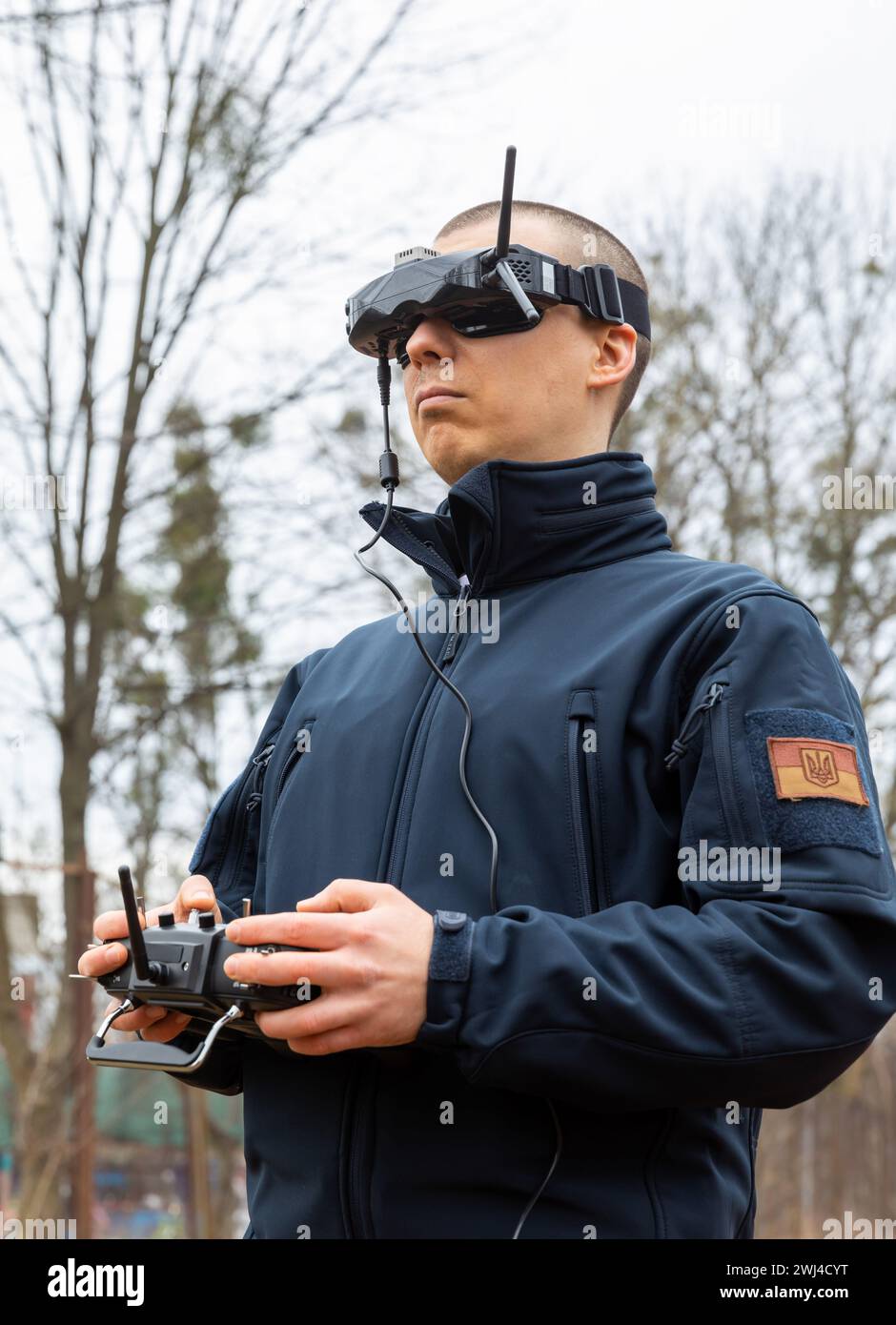 A young man wears virtual reality goggles and holds a remote control ...