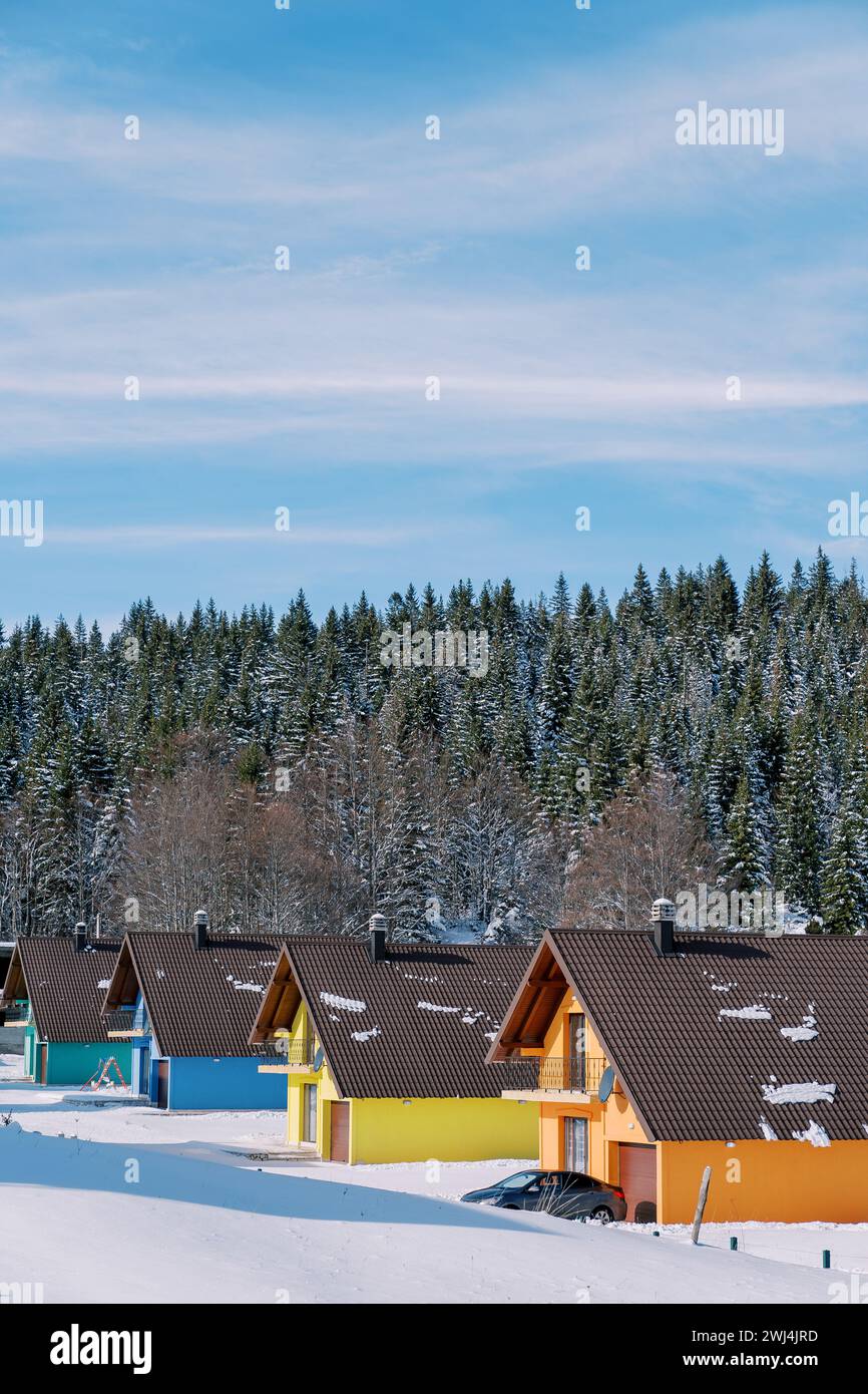 Colorful two-story cottages in a snowy resort village at the edge of a ...