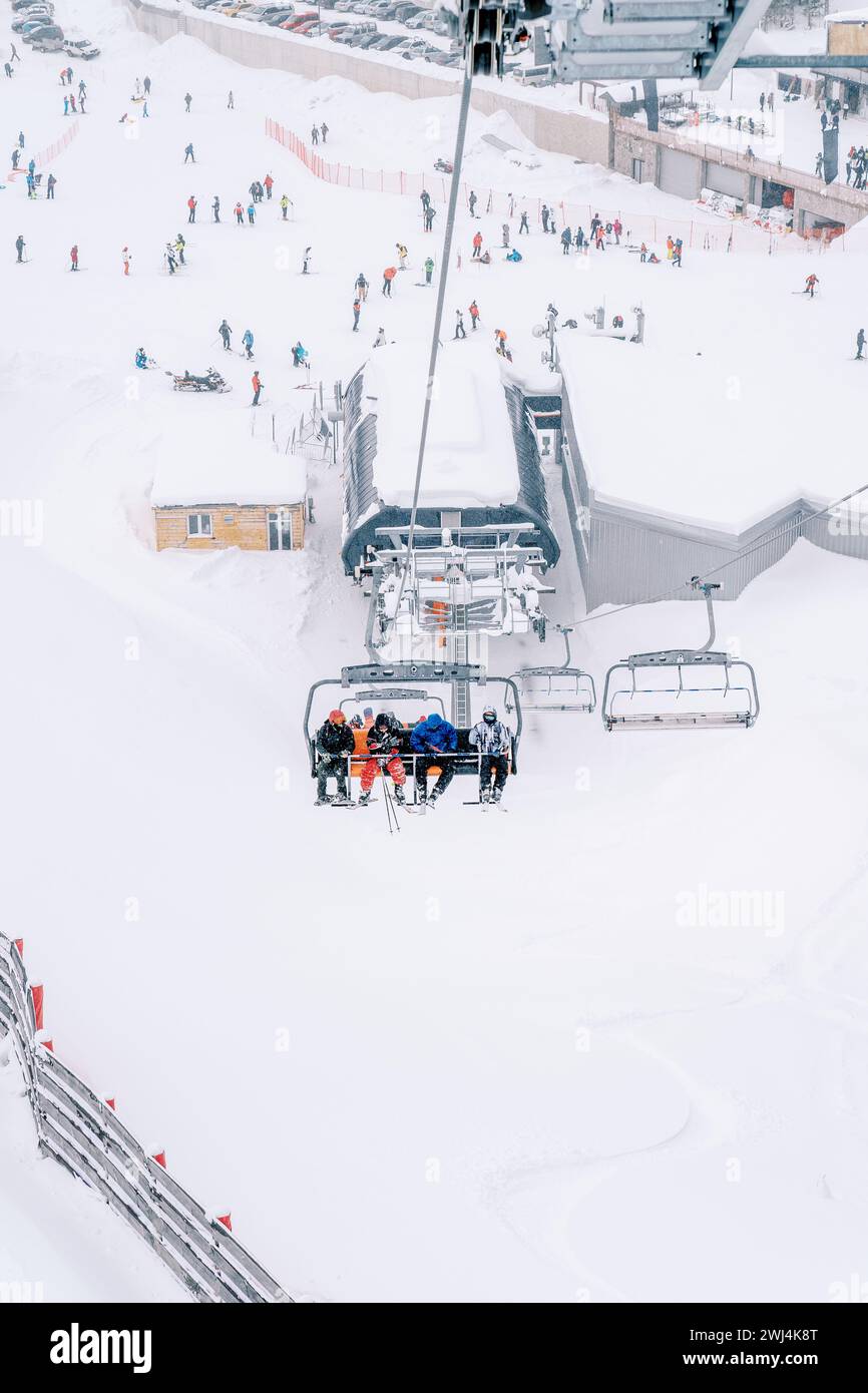 Skiers ride up the mountainside on a ski lift Stock Photo
