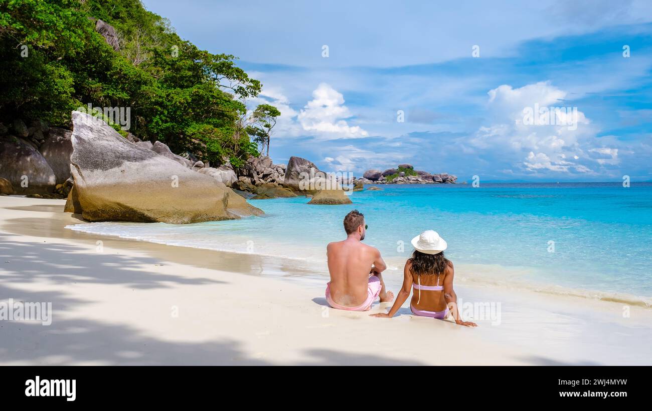 Asian women and white men relaxing on the beach in the sun at the Similan Islands Thailand Stock Photo