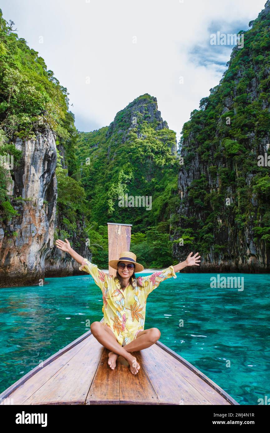 Happy Asian women in front of a longtail boat with hands up at Kho Phi Phi Thailand Stock Photo