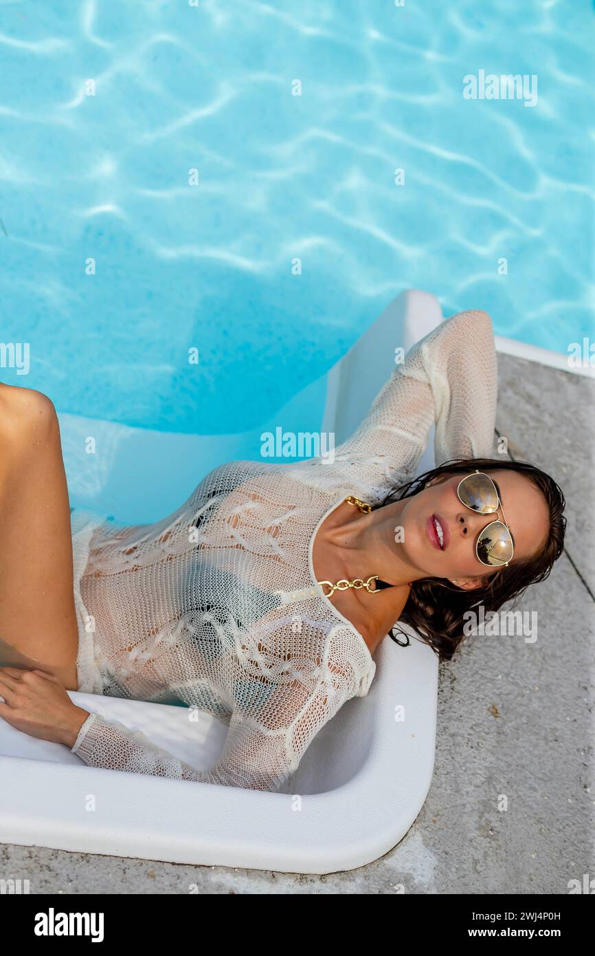 Home Haven Chic: Elegance and Relaxation with a Stunning Brunette Bikini Model in a Private Pool Oasis Stock Photo