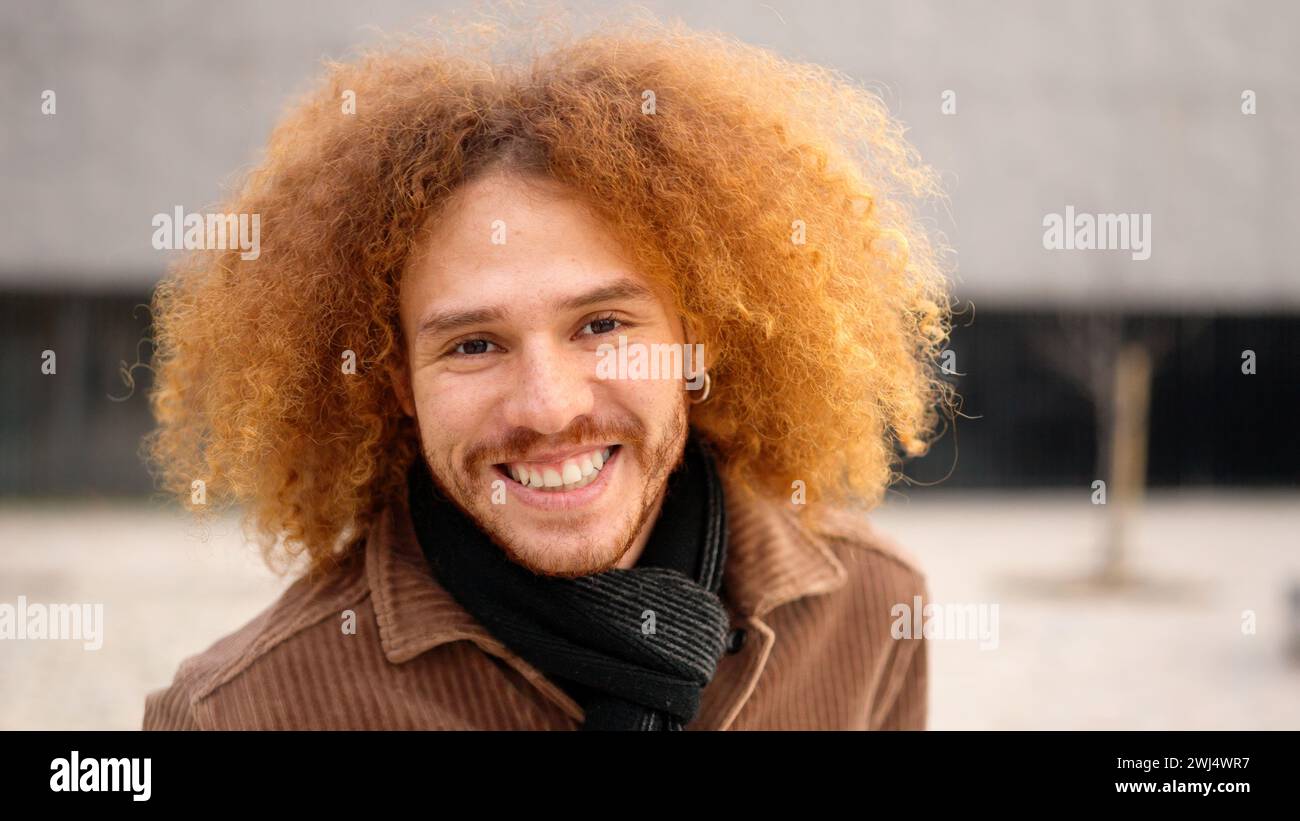 Young man with curly hair smiling at camera Stock Photo