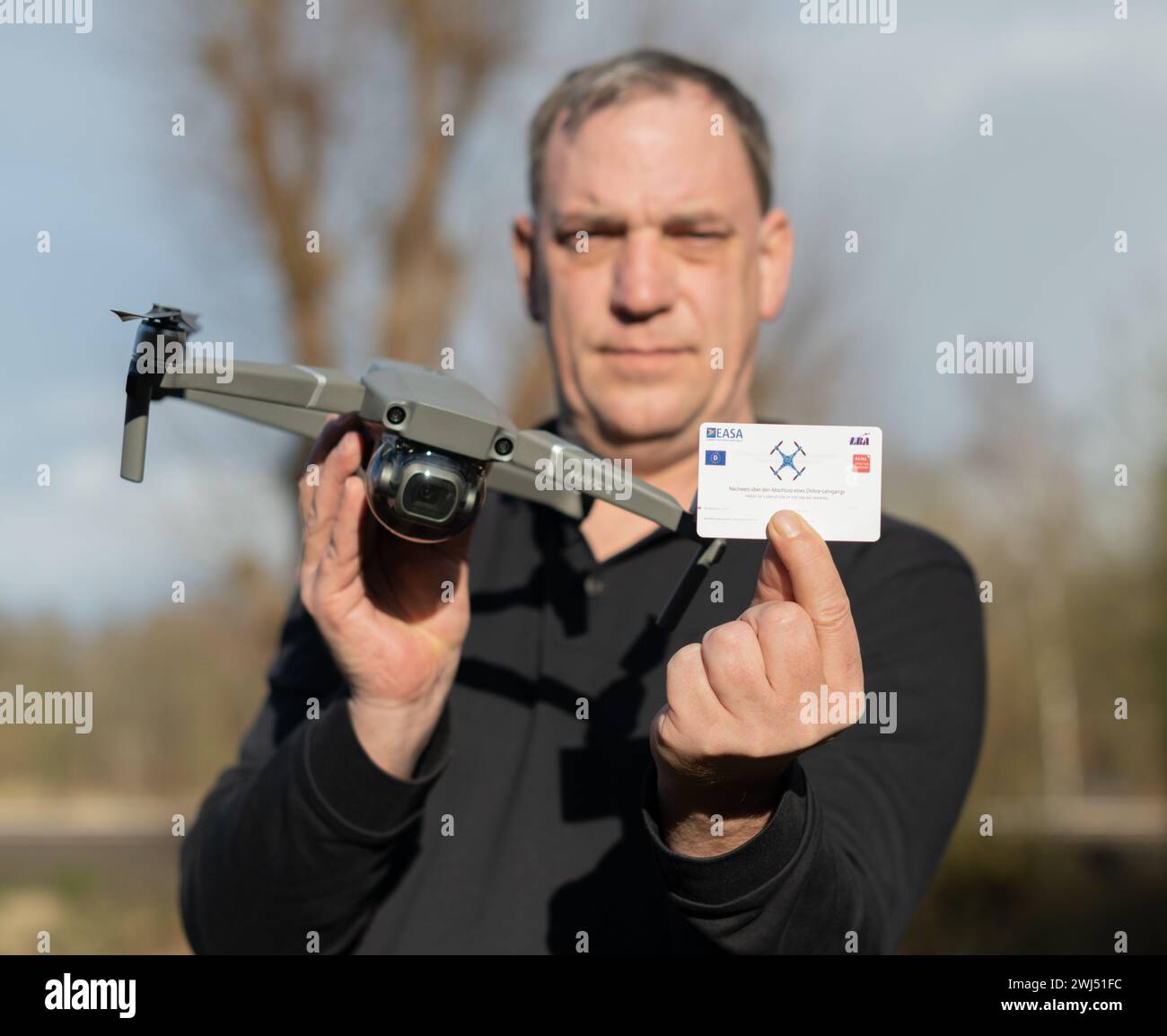 Drone pilot's license while holding a DJI Mavic Pro 2 drone and the DJI remote control in her hand Stock Photo