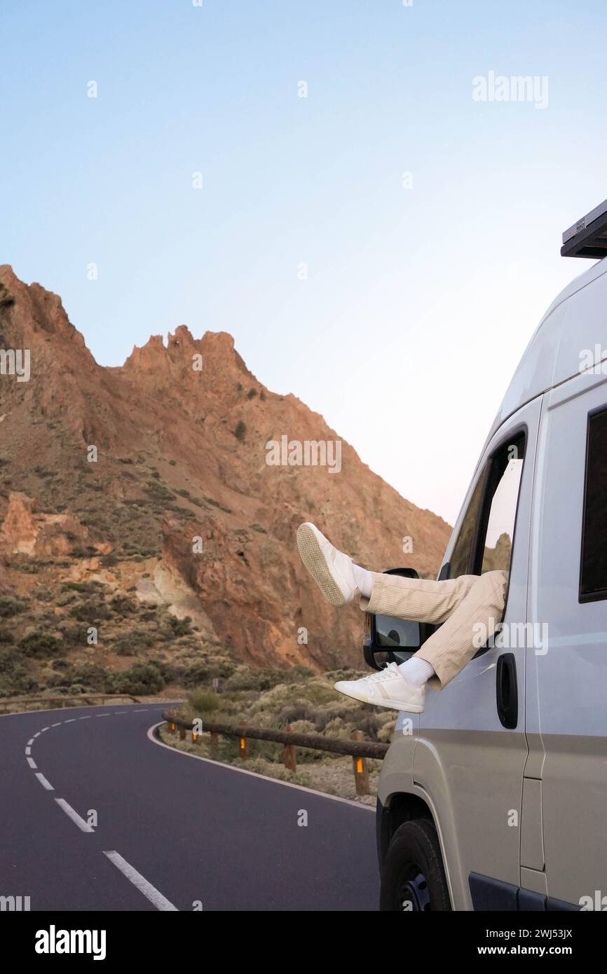 A van is parked on a winding road with rugged mountains in the ...