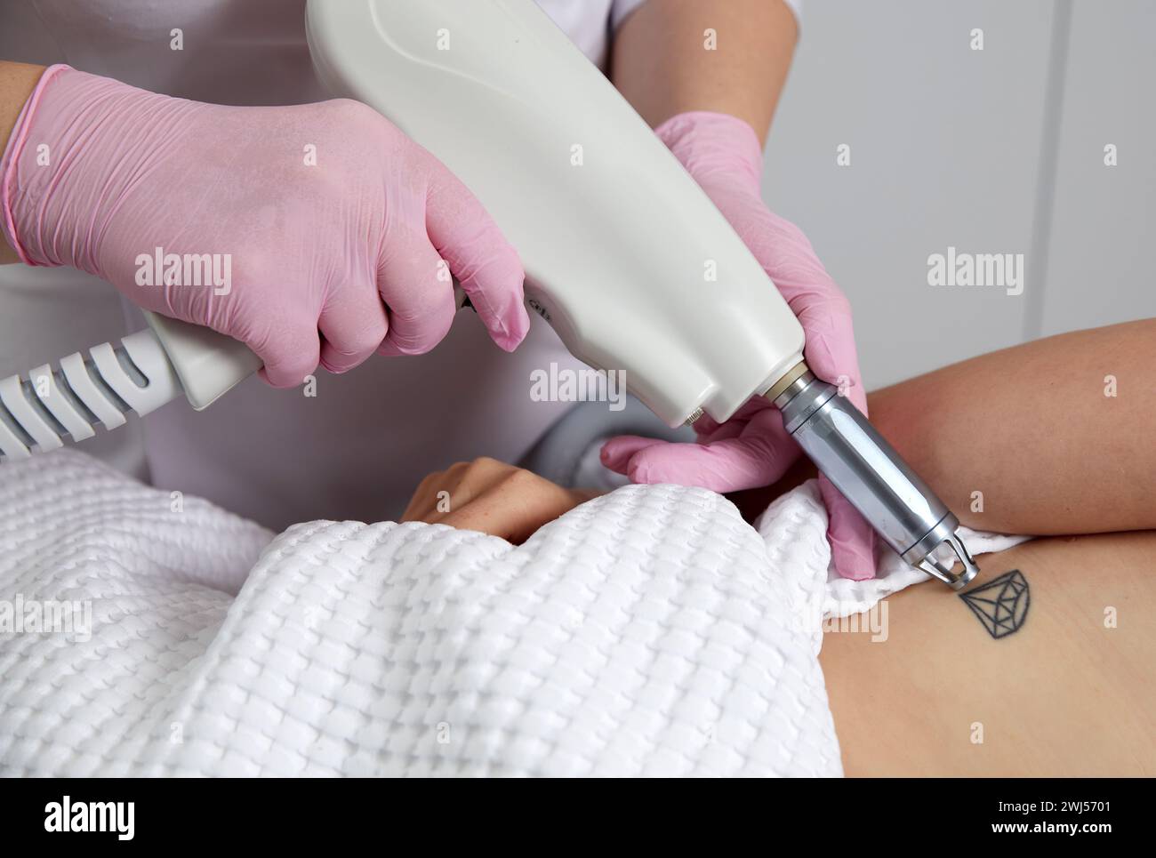 Cosmetologist using laser device to remove an unwanted tattoo from female arm. Concept of erasing tattoos as an expensive proced Stock Photo