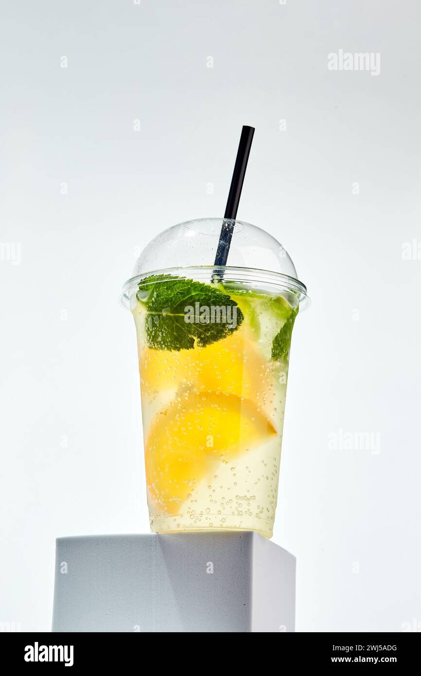 Lemonade with lemon, orange, lime and mint in transparent plastic glass on white background Stock Photo