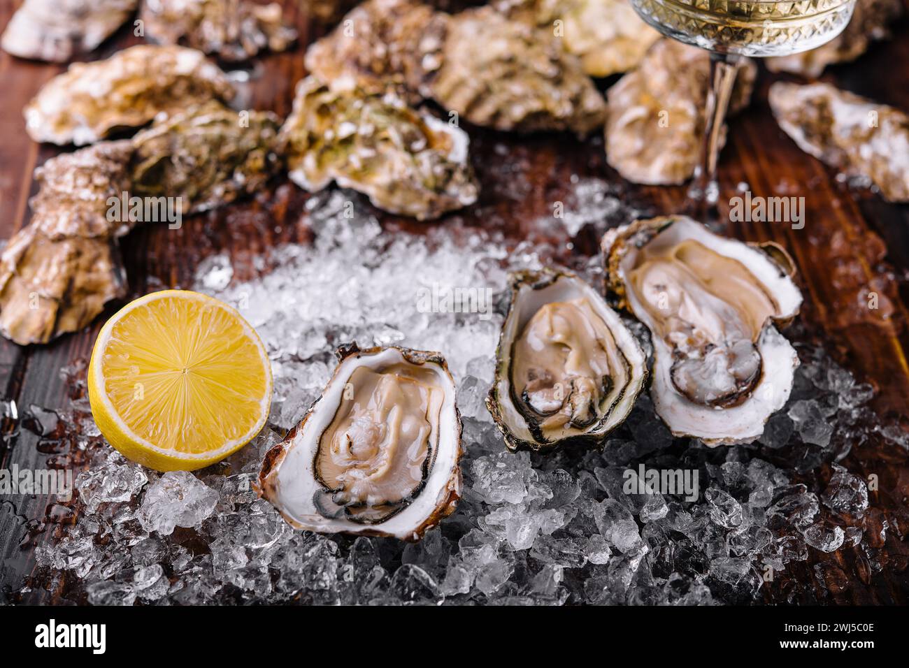 Opened oysters, ice and lemon on board Stock Photo