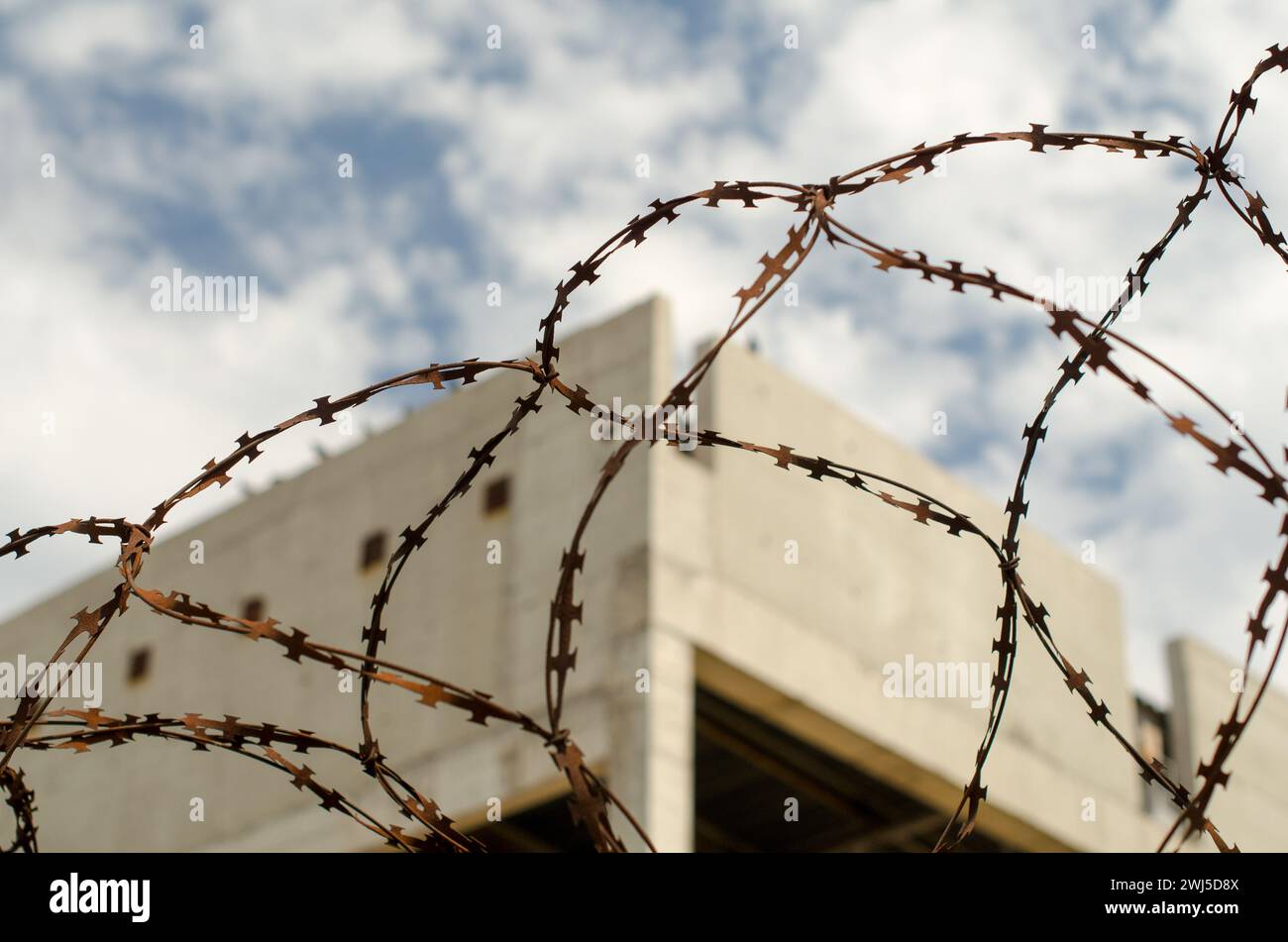 Rusty barbed wire fence against the backdrop of an abandoned bui Stock Photo