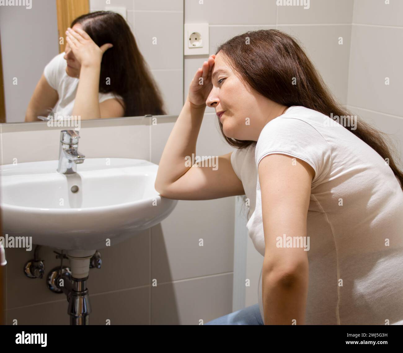 A pregnant woman struggling with morning sickness in the bathroom Stock Photo