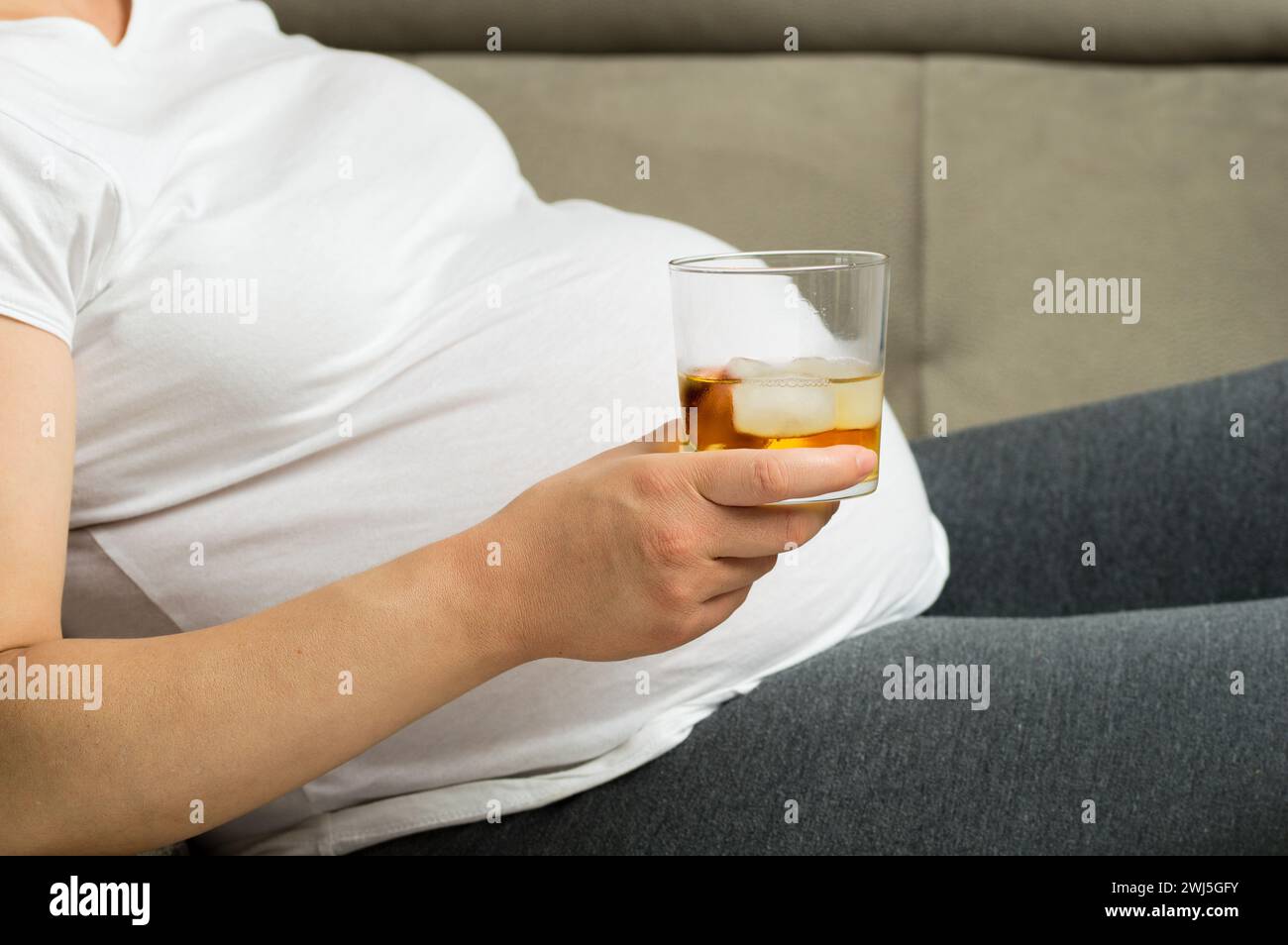 Irresponsible pregnant woman drinking alcohol at home Stock Photo