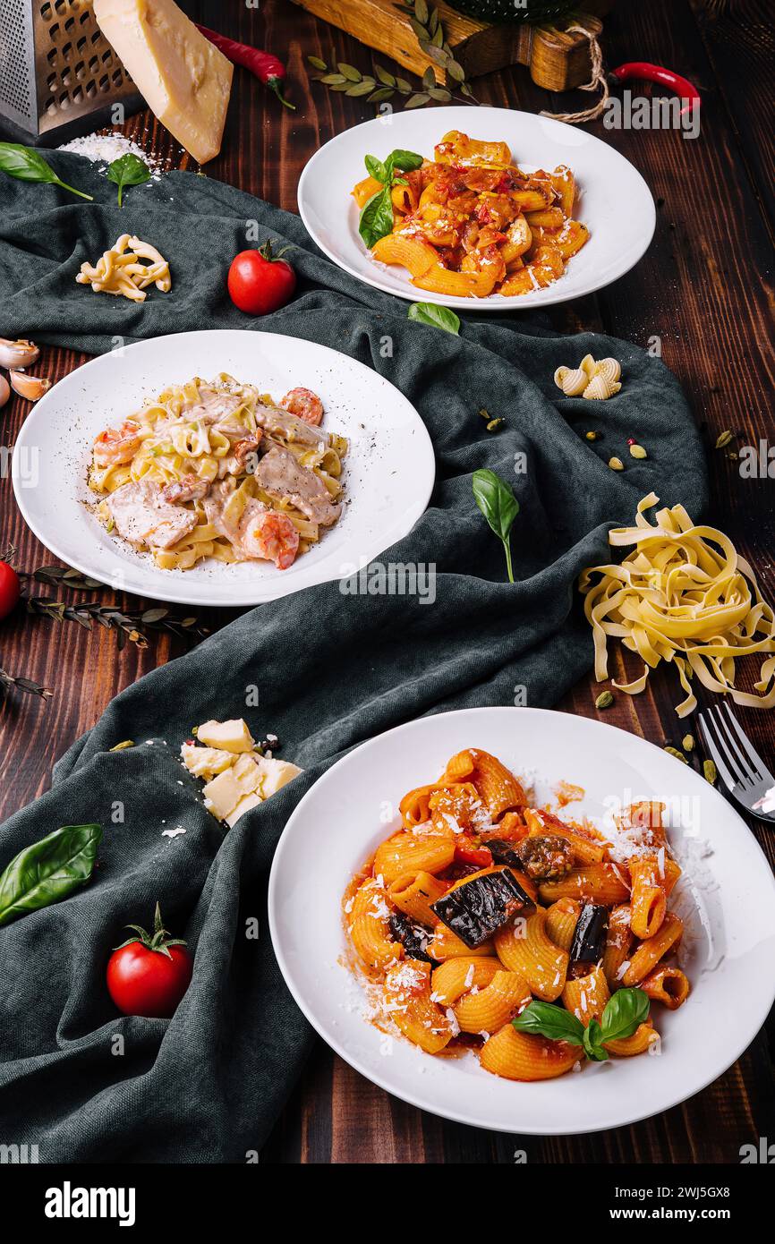 Different pasta dishes on wooden with fabric background Stock Photo