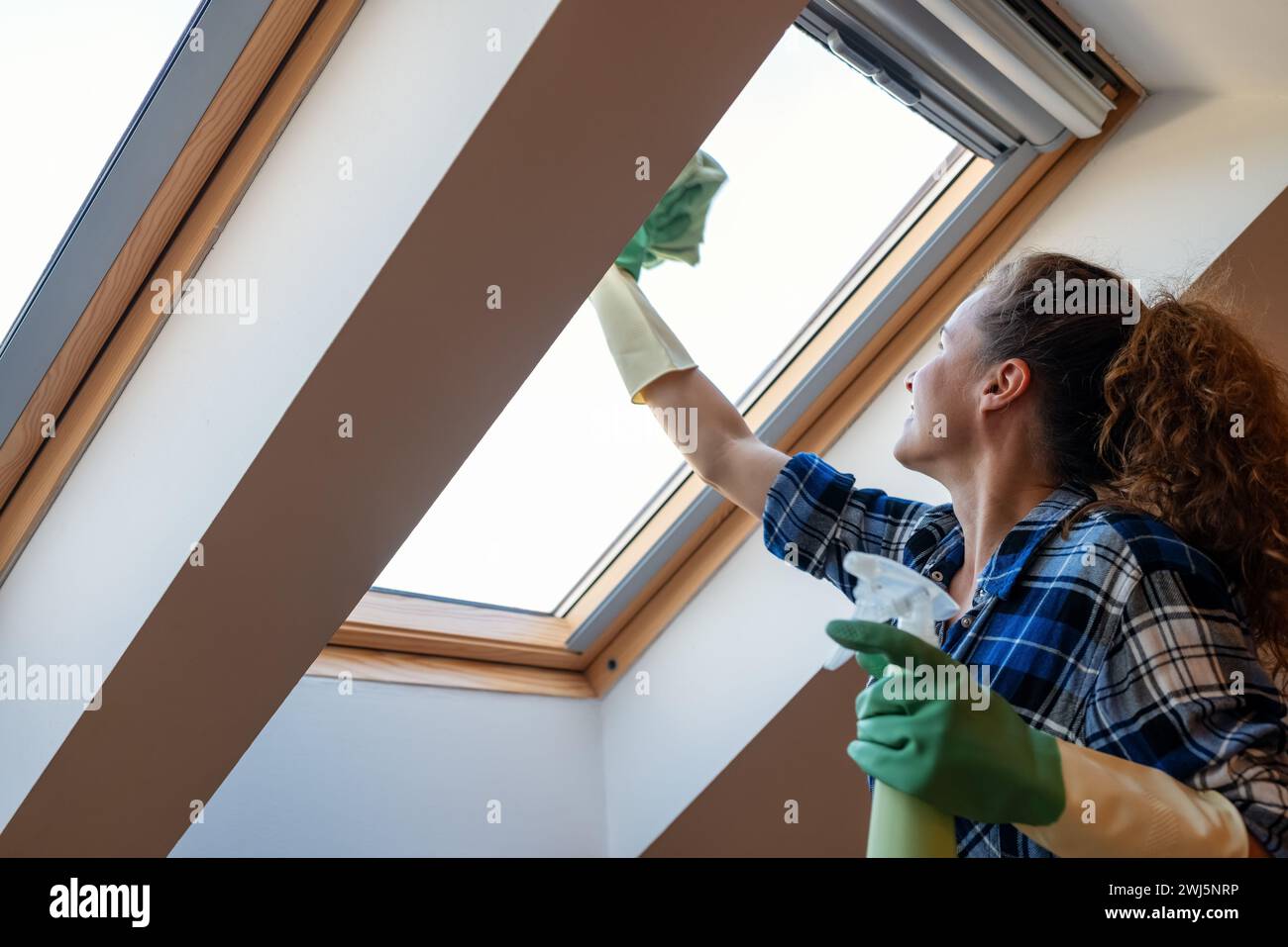 Woman washes skylight window at home. Housework, keeping house clean and tidy. Stock Photo