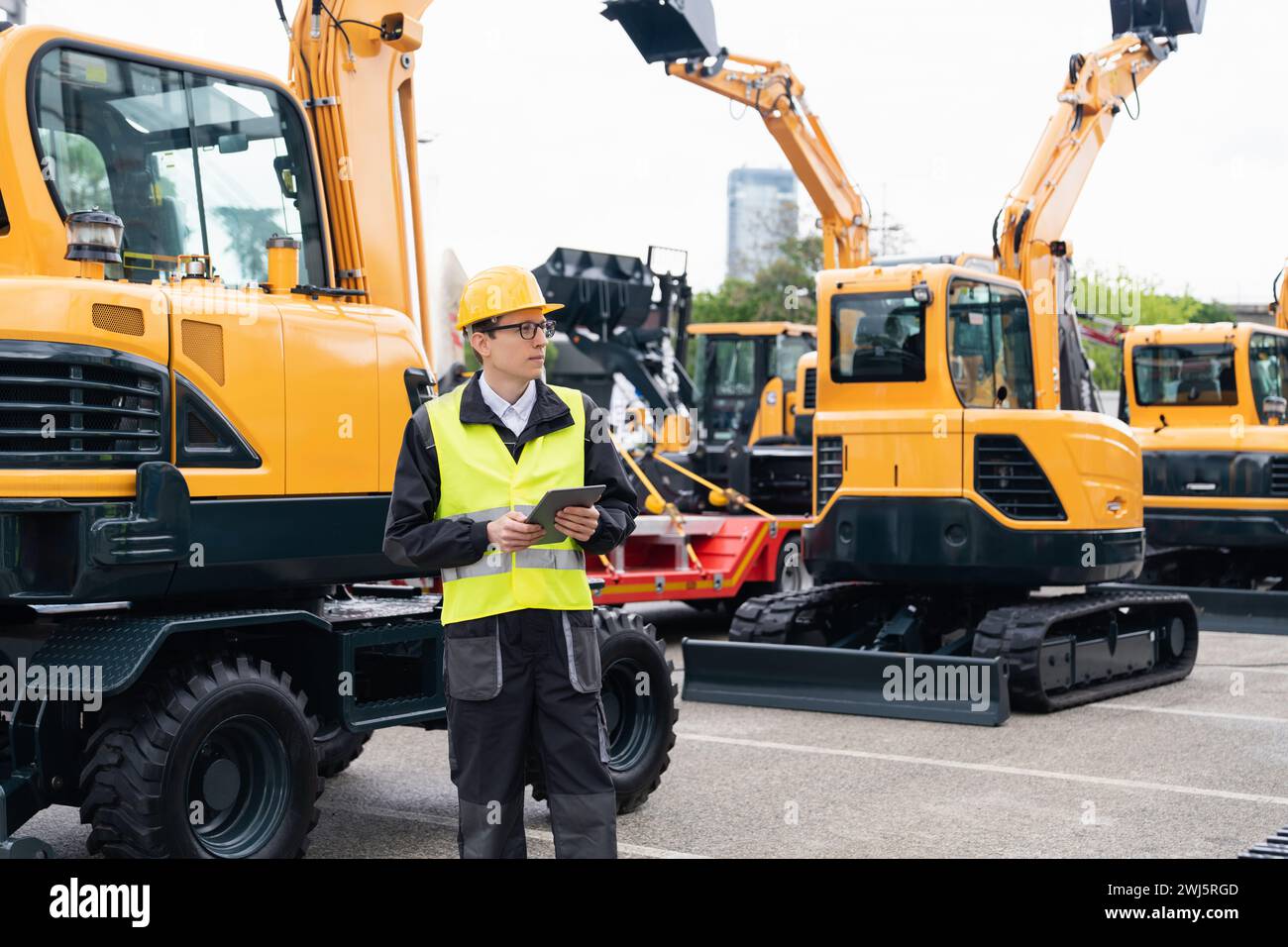 Engineer in a helmet with a digital tablet stands next to construction ...