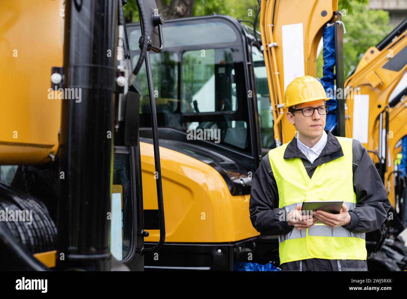 Engineer in a helmet with a digital tablet stands next to construction ...