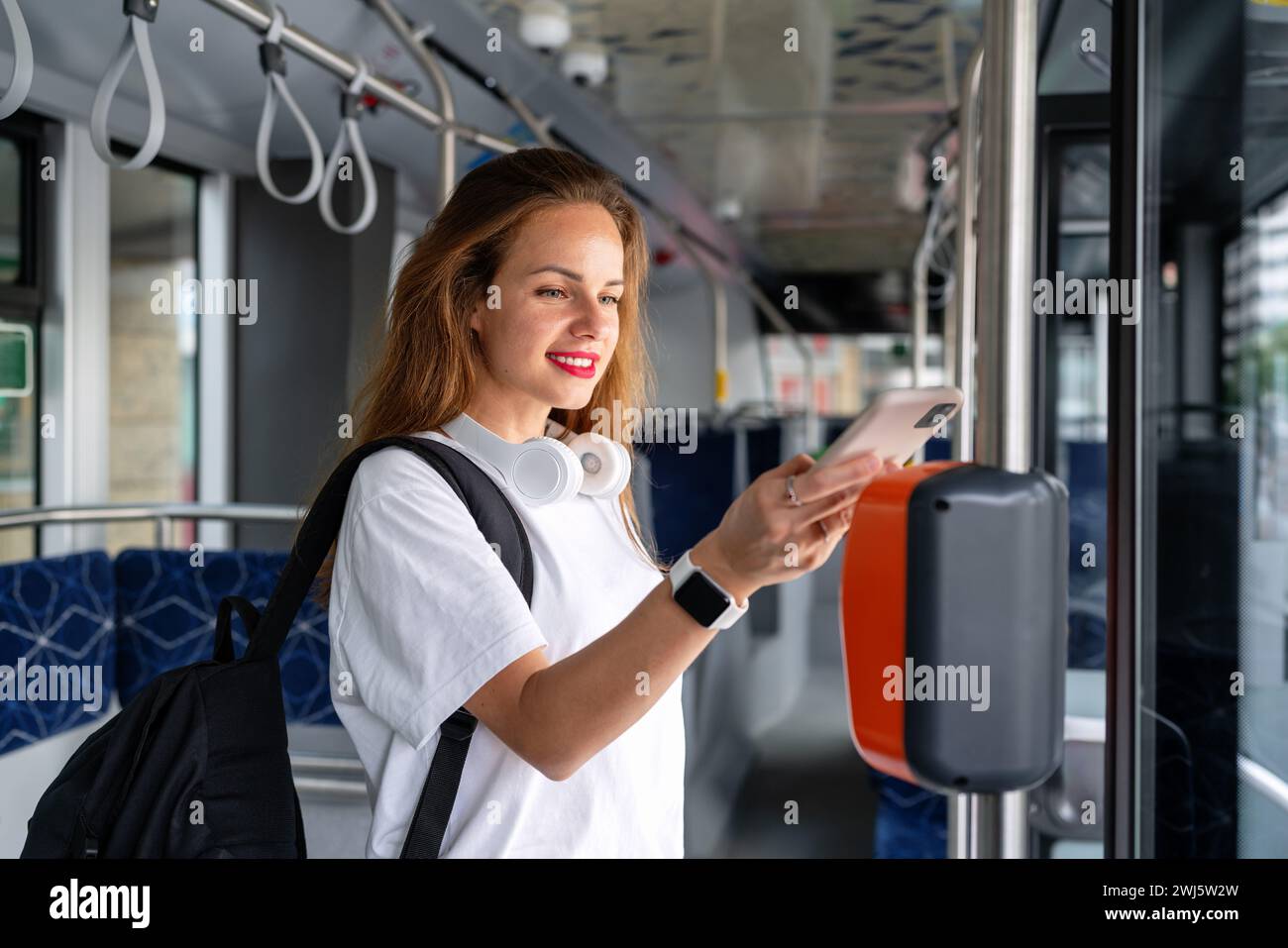 Woman paying bus with her smartphone and contactless technology for mobile payment. Stock Photo