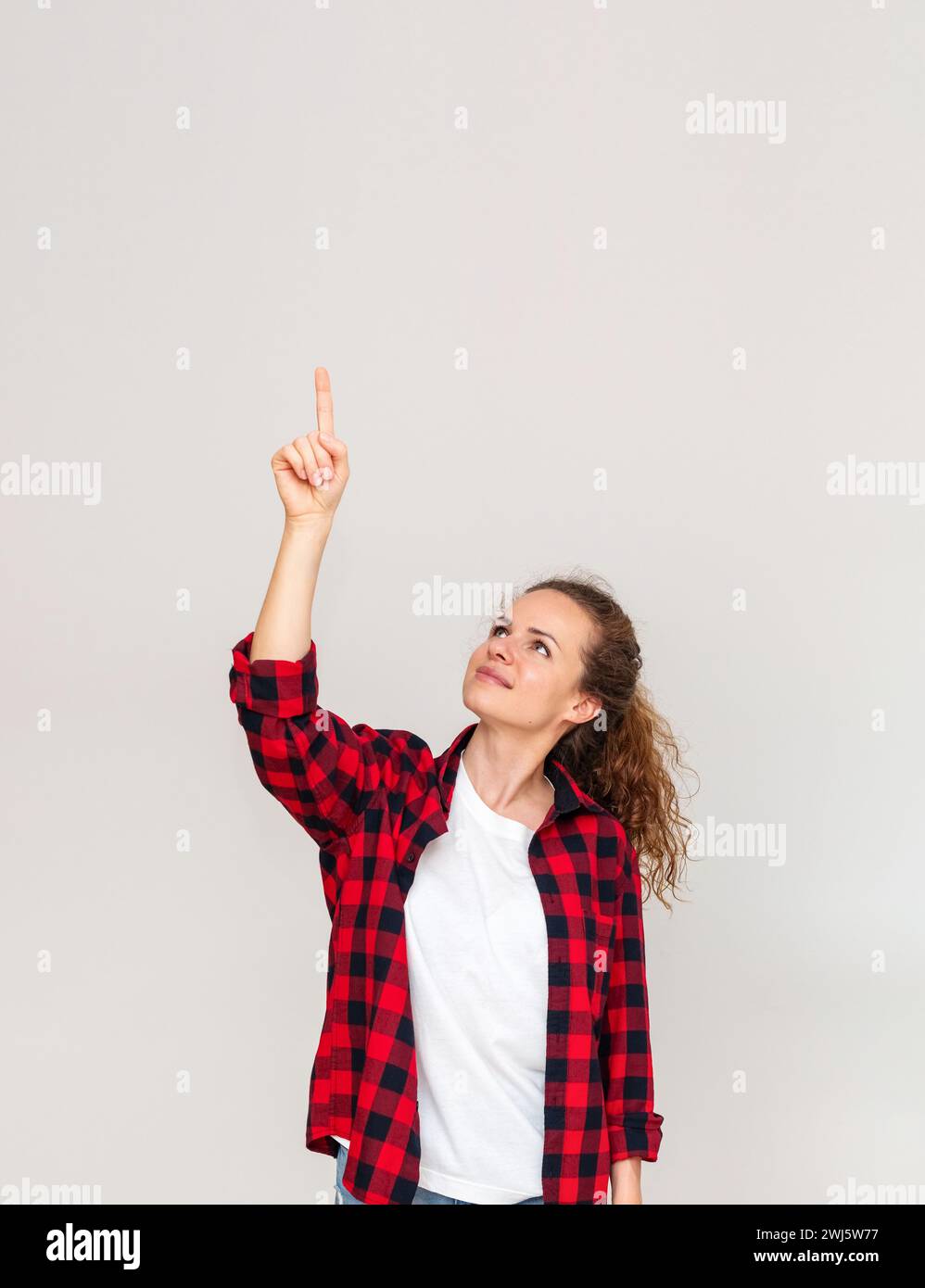 Young woman pointing finger up or touching virtual screen with finger. Stock Photo