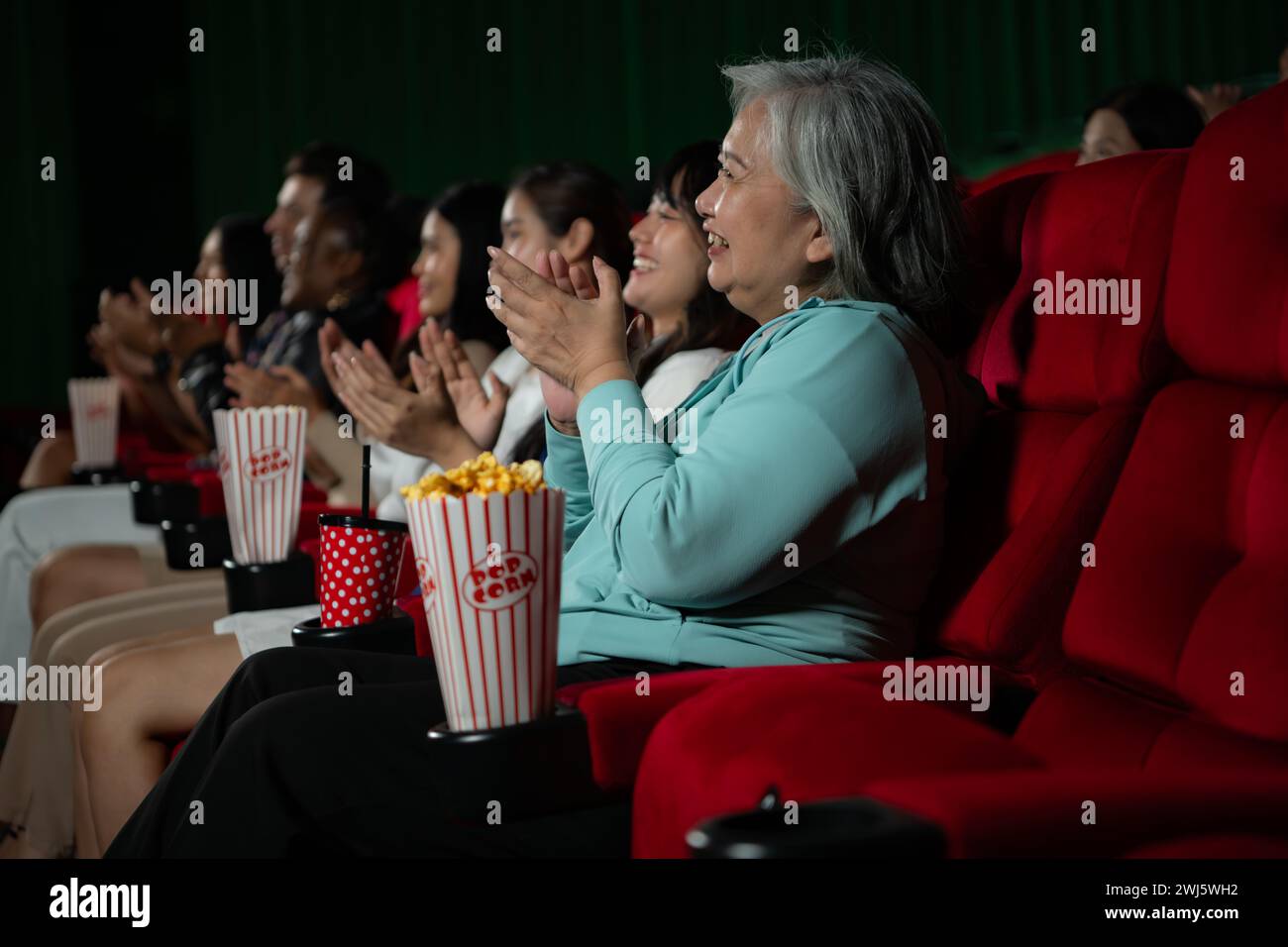 Family members of an Asian senior woman clap their hands for the movies she watches with the impression Stock Photo