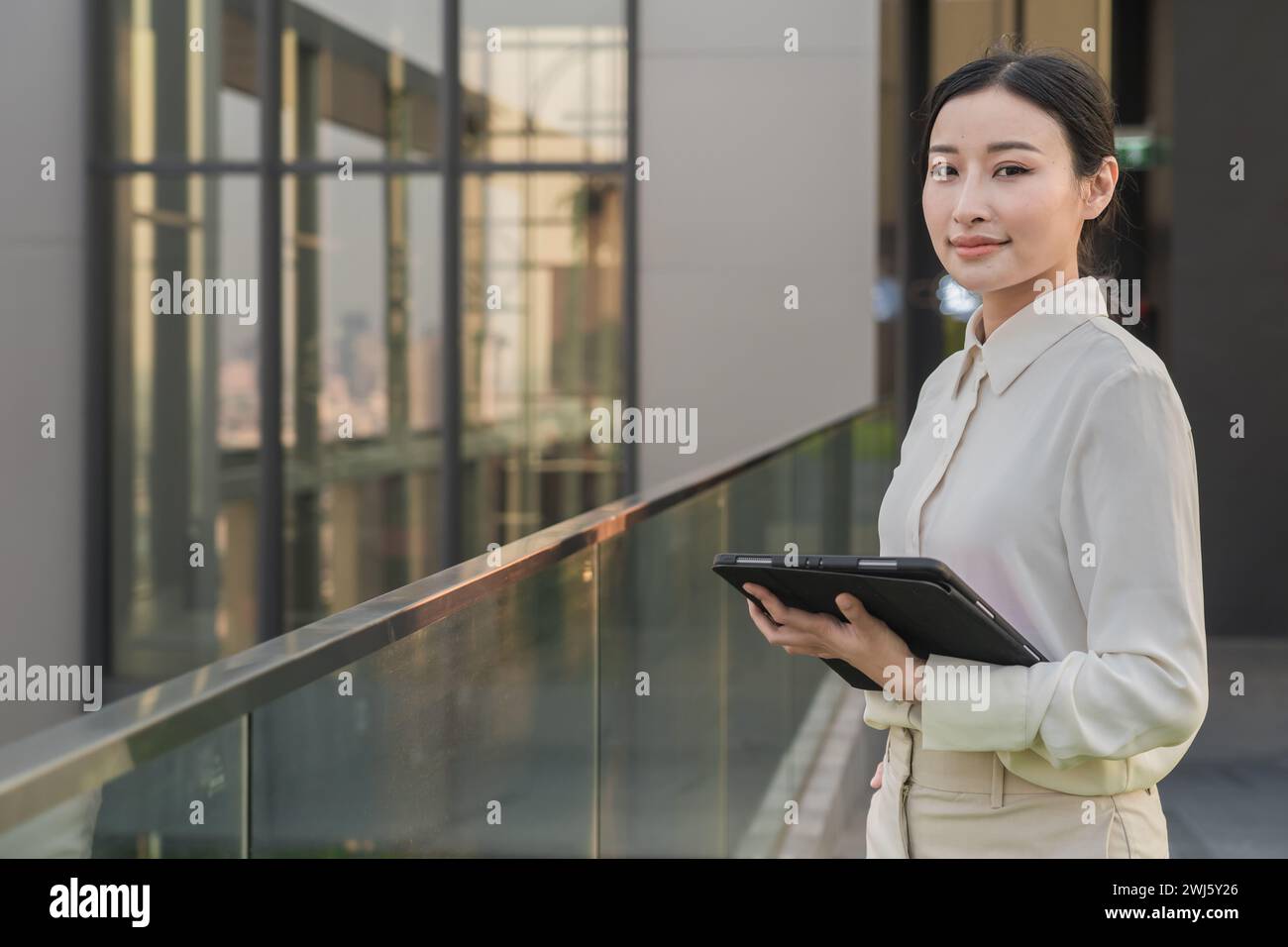A young Asian woman on a balcony with a tablet, AI-generated. Stock Photo