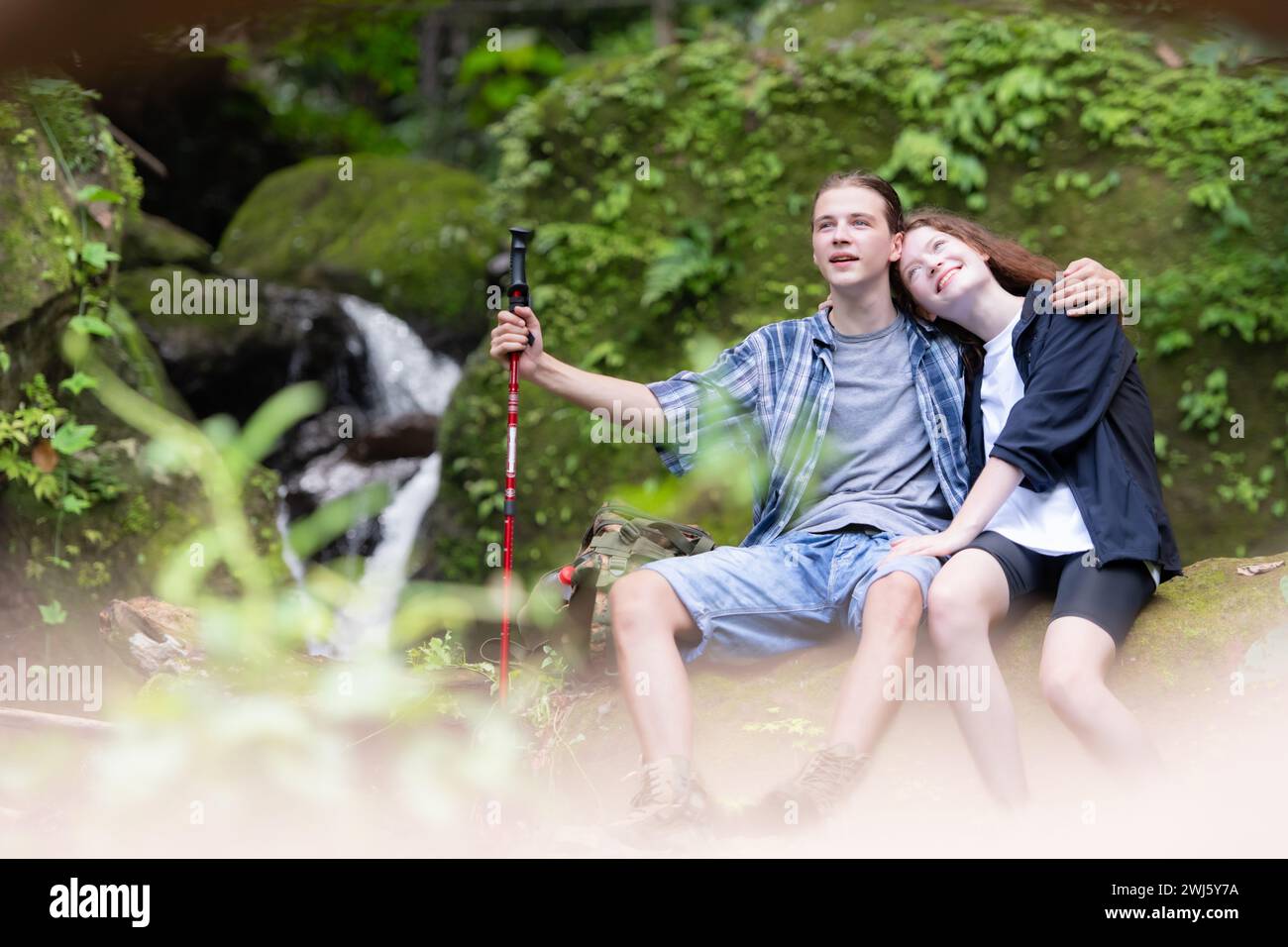 Young couple hiking in the forest with backpacks and trekking poles Stock Photo