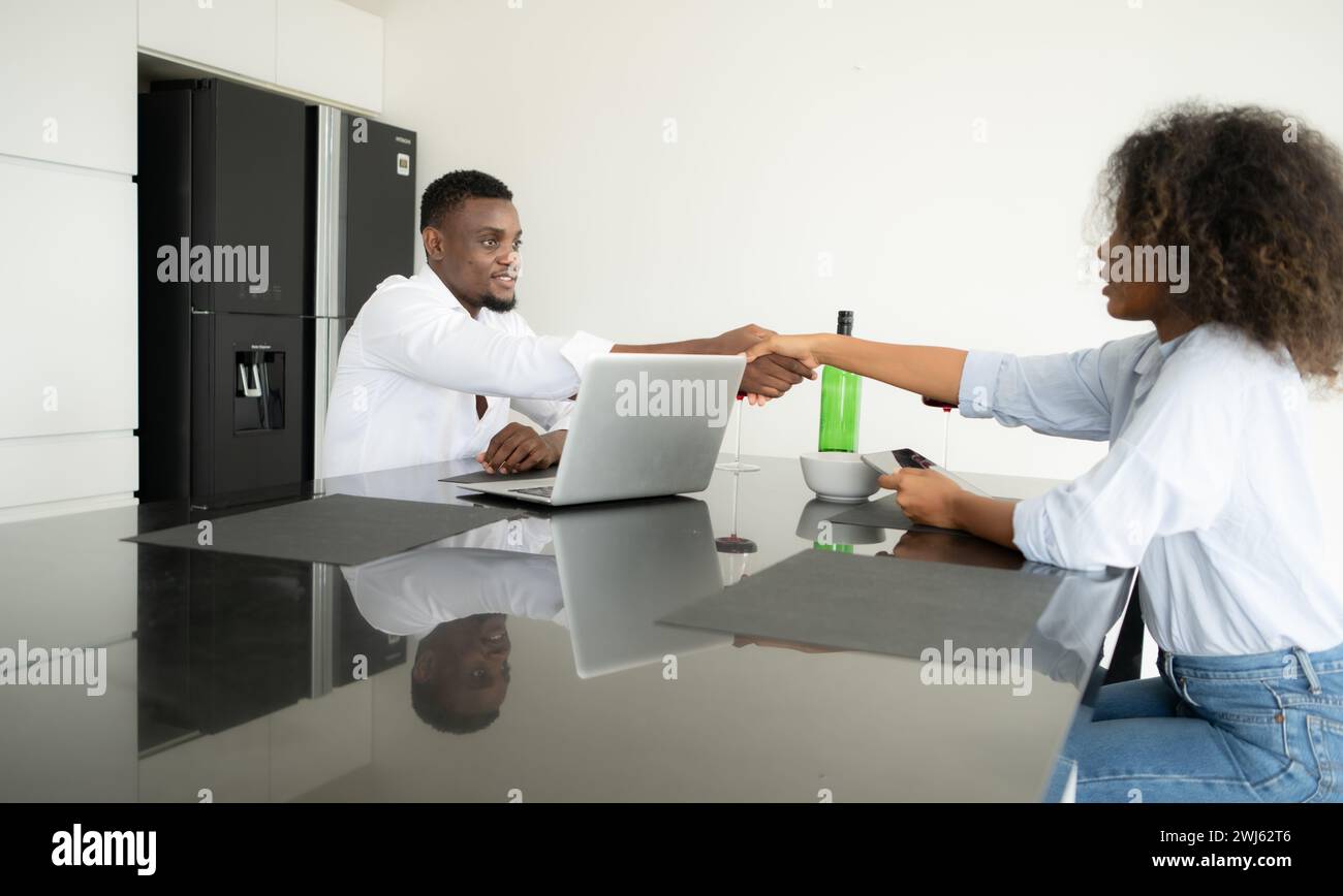 Both of young businesses drinking wine and use their laptops to share information with each other in their living room of house. Stock Photo