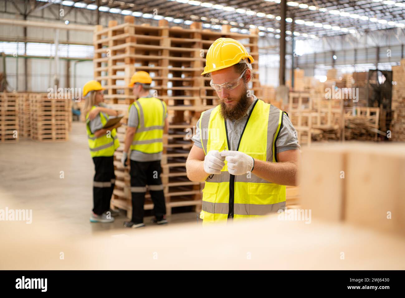 Young workers working in a woodworking factory, Using a hammer to work assembling pallet parts Stock Photo