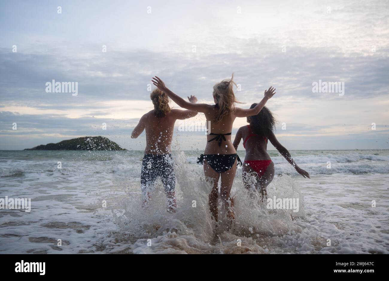 Embracing our natural bodies at the beach. Three topless young women  smiling at the camera while wearing bikini bottoms. Group of happy female  friends having fun and enjoying their vacation. stock photo