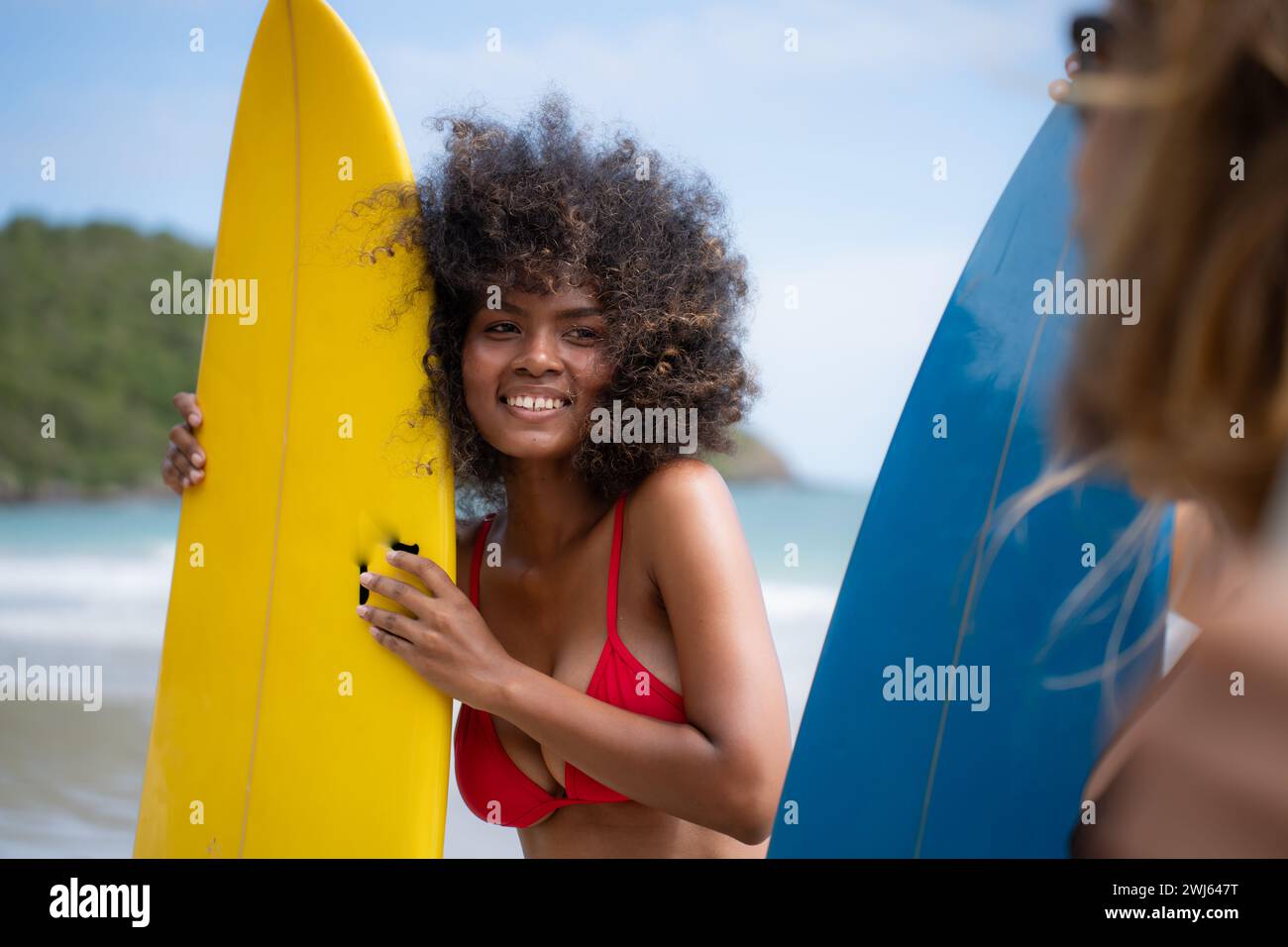 Portrait of smiling young woman in bikini with surfboard at beach Stock Photo