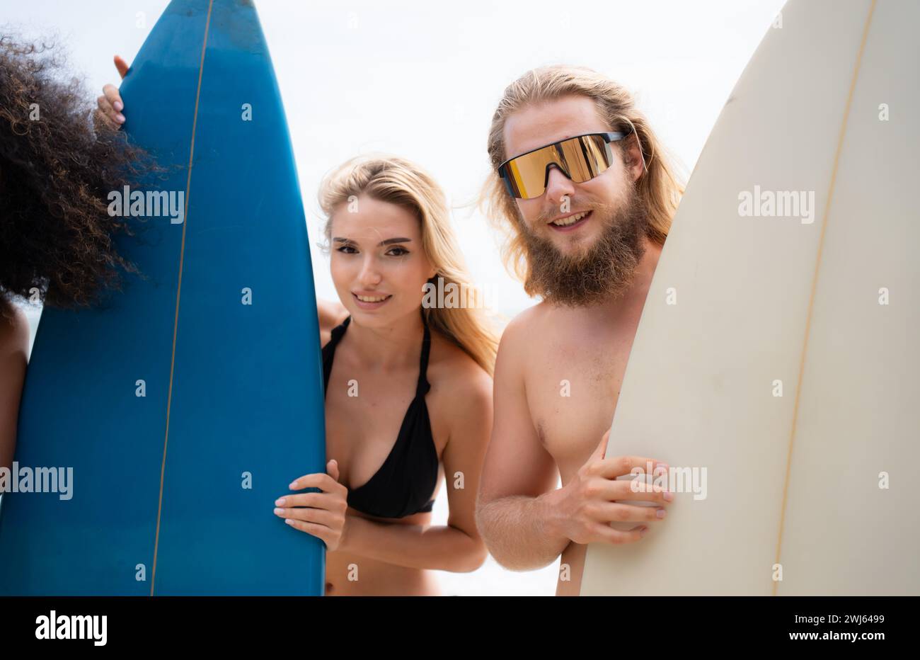 Portrait of smiling young woman in bikini with surfboard at beach Stock Photo