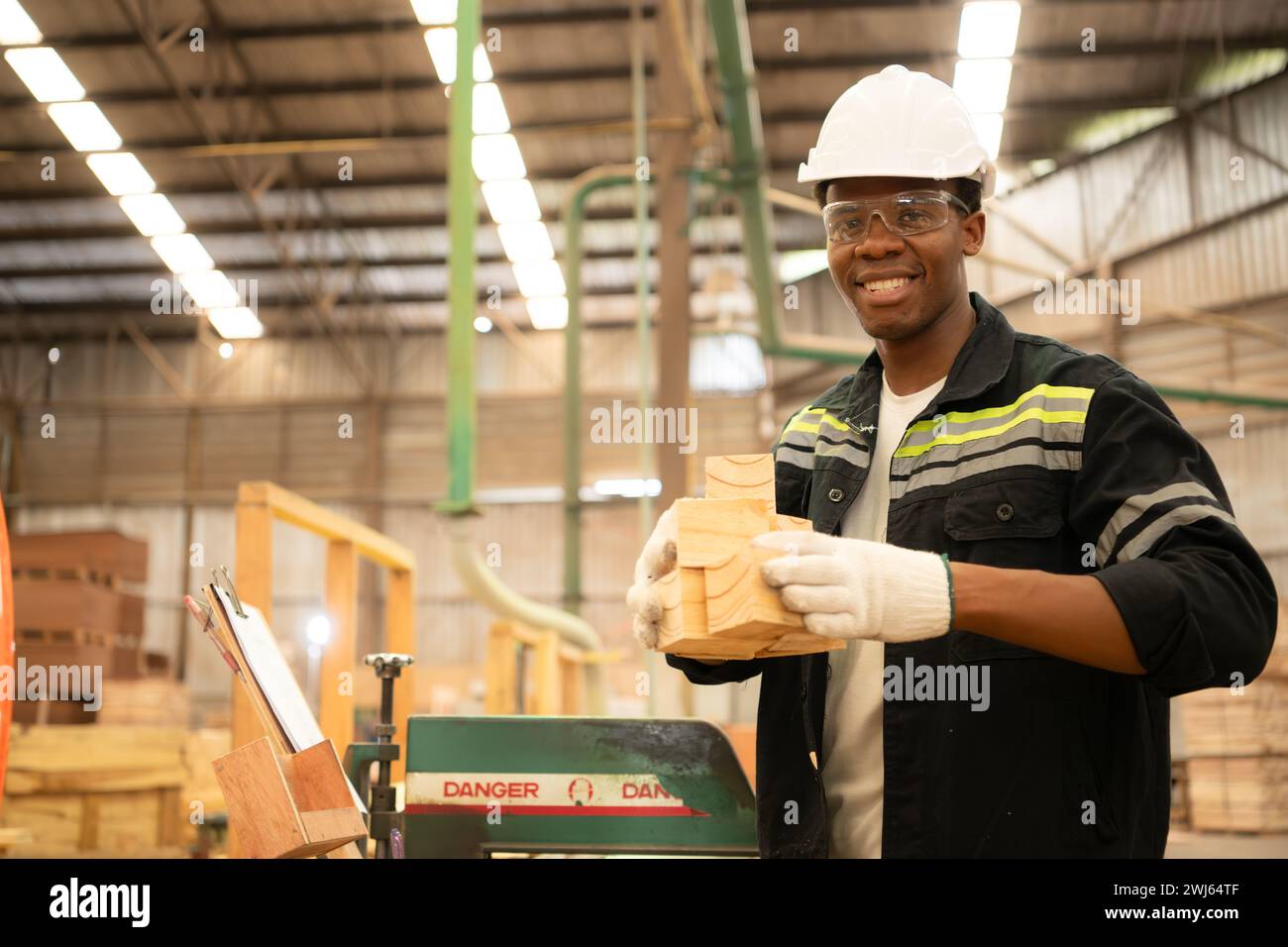 Young man worker work in a woodworking factory, Working with wood sawing and cutting machines to produce wooden sheets for makin Stock Photo