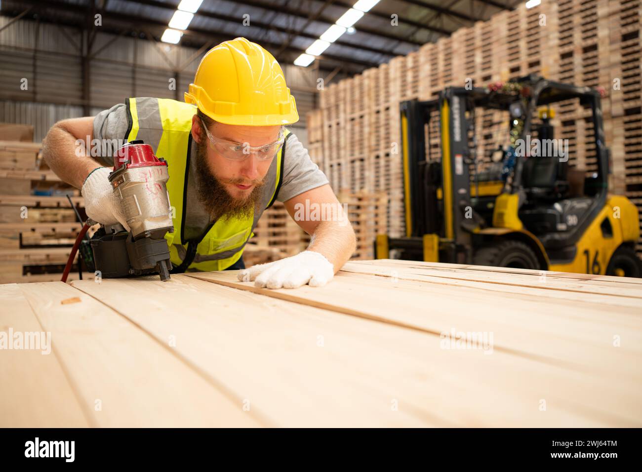 Young workers working in a woodworking factory, Using a nailing machine to assemble wooden pallets Stock Photo