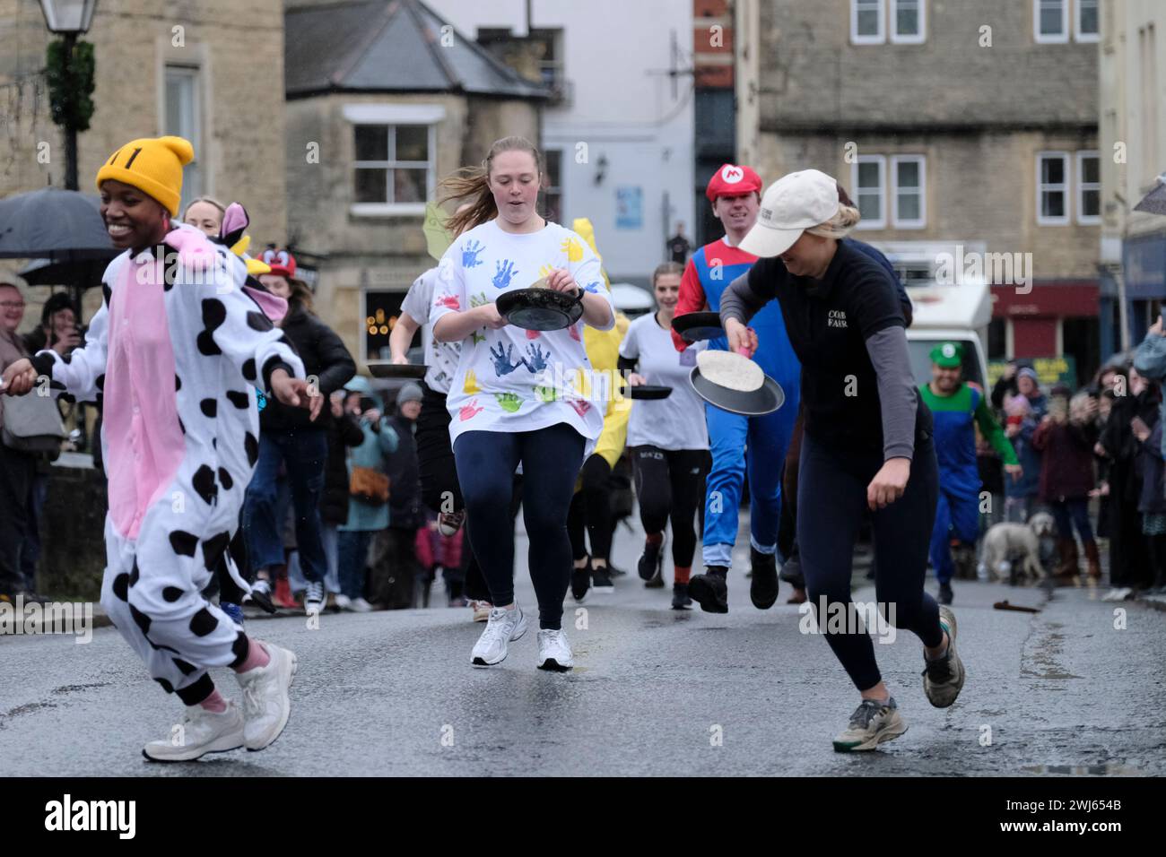 Bradford-on Avon, Wiltshire, UK. 13th Feb, 2024. The annual pancake race along the town bridge in Wiltshire's historic Bradford-on-Avon. The main road is closed for a few minutes each Shrove Tuesday for this traditional light-hearted race; the route is over the Bridge and back again. Each pancake must be tossed at least three times along the route, otherwise the competitor is disqualified. Shrove Tuesday is a Christian Feast Day before the start of Lent, an opportunity to use up fats and sugars before fasting. Credit: JMF News/Alamy Live News Stock Photo