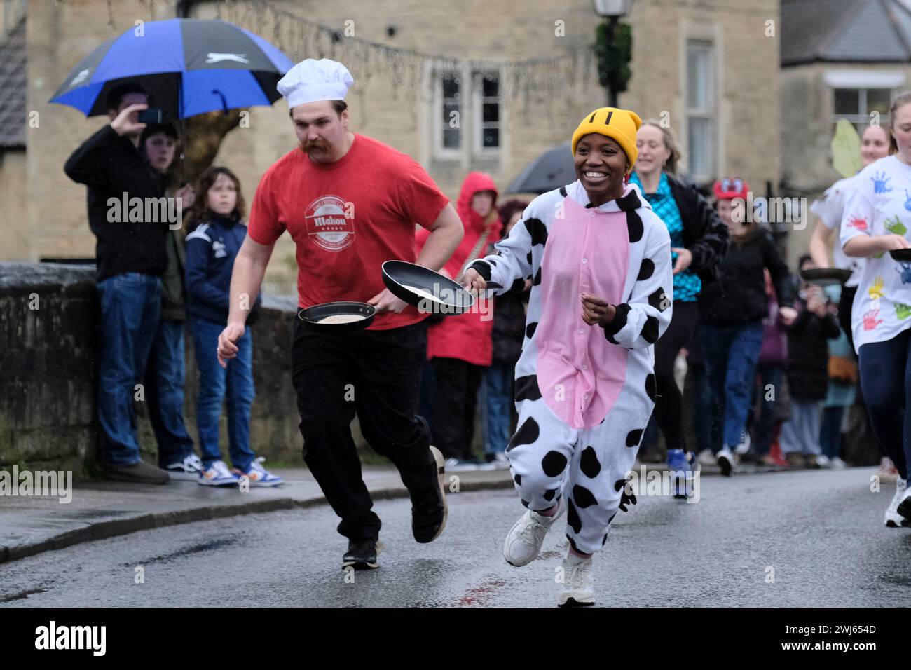 Bradford-on Avon, Wiltshire, UK. 13th Feb, 2024. The annual pancake race along the town bridge in Wiltshire's historic Bradford-on-Avon. The main road is closed for a few minutes each Shrove Tuesday for this traditional light-hearted race; the route is over the Bridge and back again. Each pancake must be tossed at least three times along the route, otherwise the competitor is disqualified. Shrove Tuesday is a Christian Feast Day before the start of Lent, an opportunity to use up fats and sugars before fasting. Credit: JMF News/Alamy Live News Stock Photo