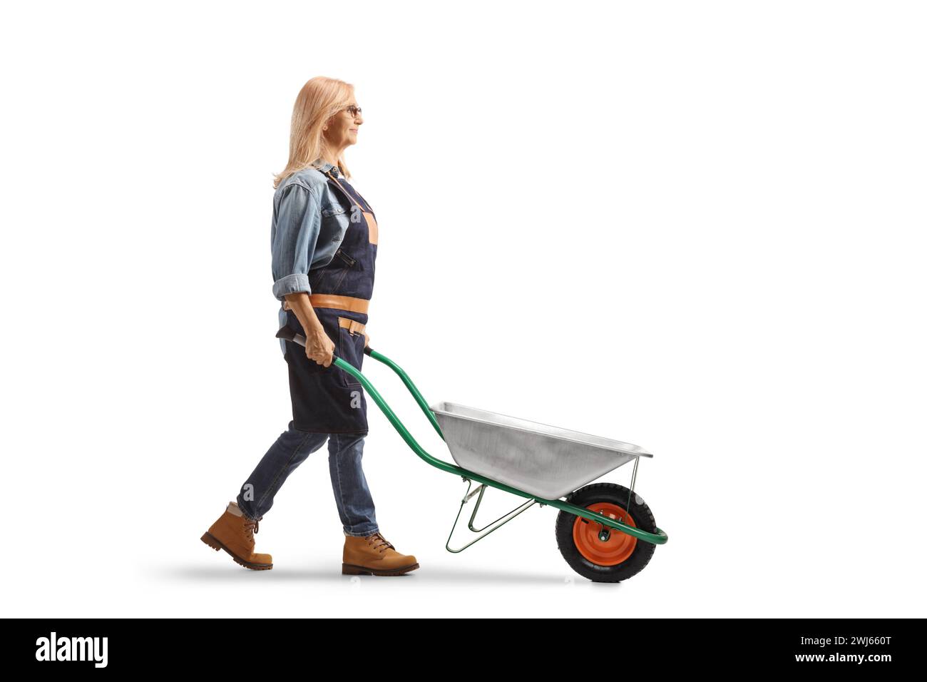 Full length profile shot of a female farmer pushing a wheelbarrow isolated on white background Stock Photo