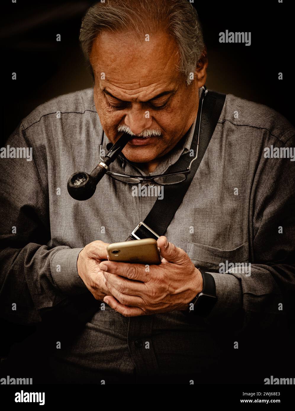 Smart Elderly man sending a text message on the smartphone while smoking a pipe. Portrait on a smart elderly man on a smart phone while smoking a pipe Stock Photo