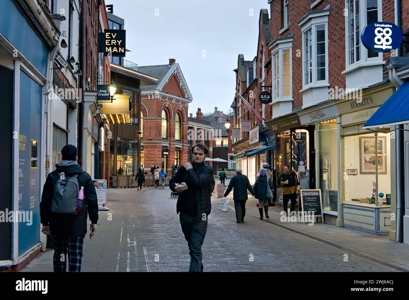 people walking by Lit-up shops near the Cornhill Quarter in Lincoln Stock Photo