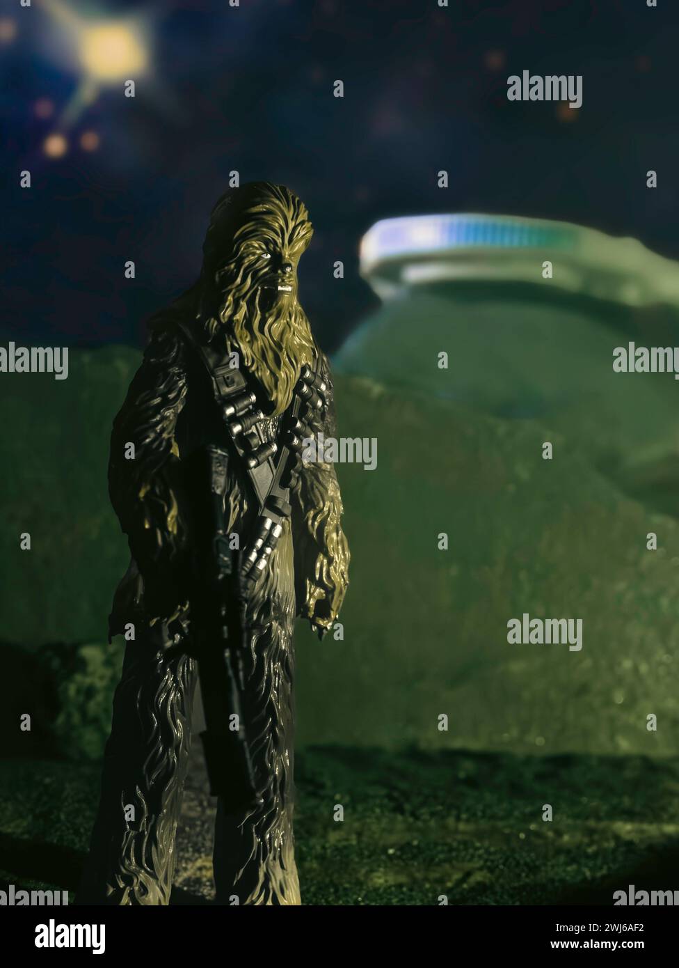 Chewbacca figure placed on a rocky planet with the Millennium Falcon in the background against a starry sky Stock Photo