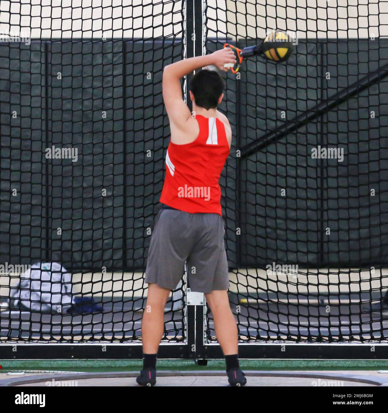 A high school boy spinning a 25 pound weight over his head while competing in the weight throw. Stock Photo