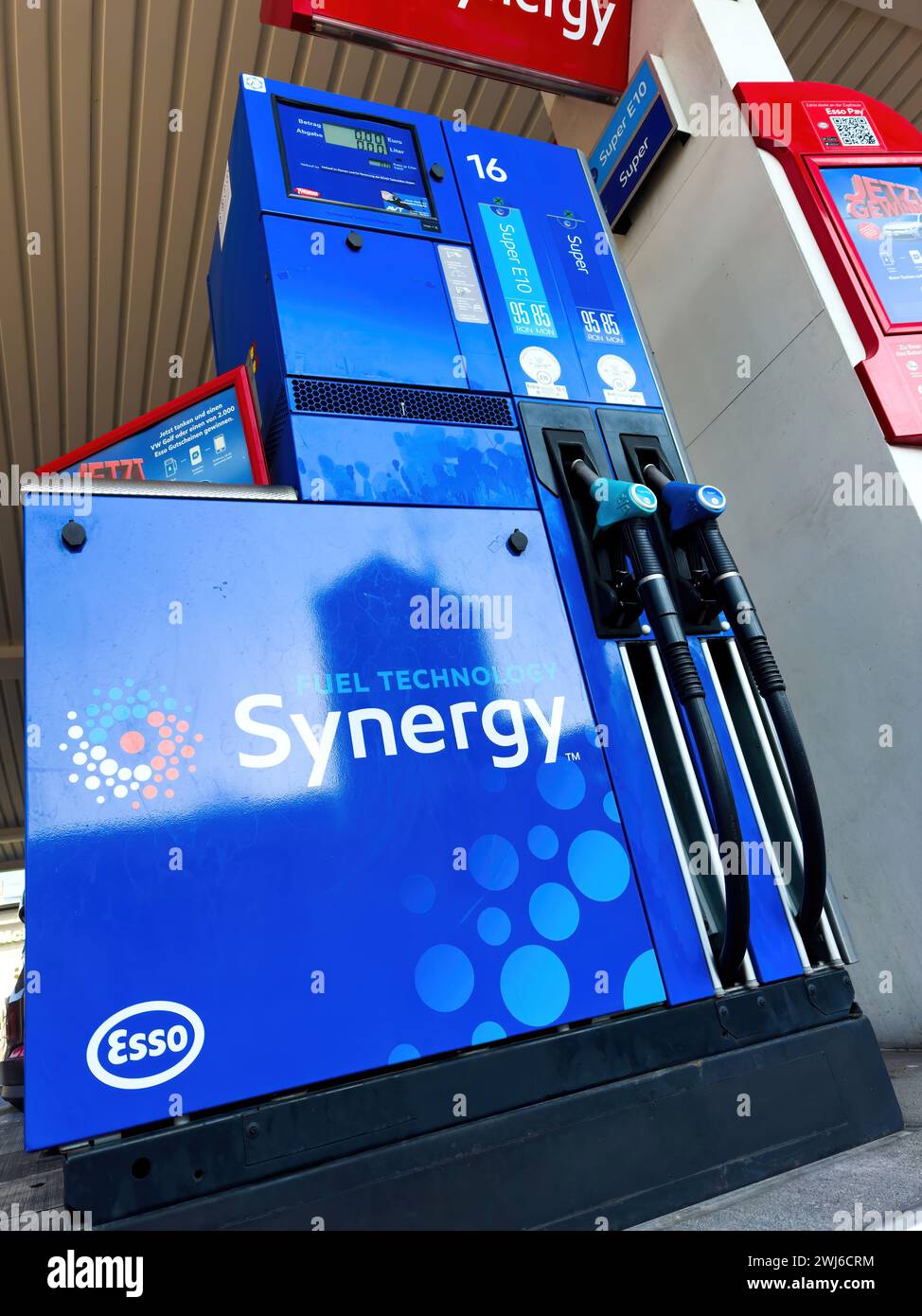 A blue Esso Synergy gas pump sits next to a gas station, ready to provide fuel for vehicles. Stock Photo