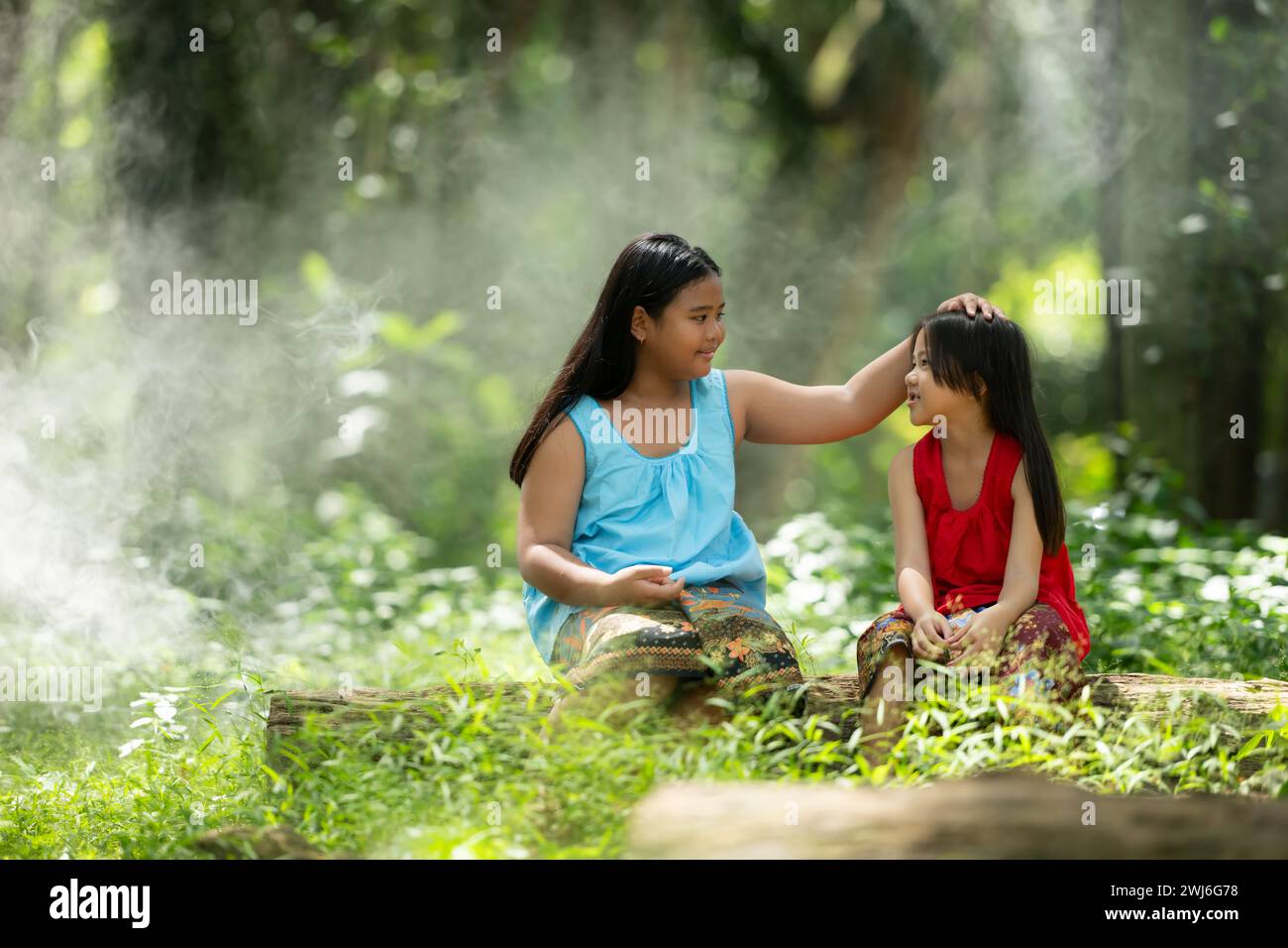 Two girls Asian women with traditional clothing stand had fun playing together in the rainforest. Stock Photo