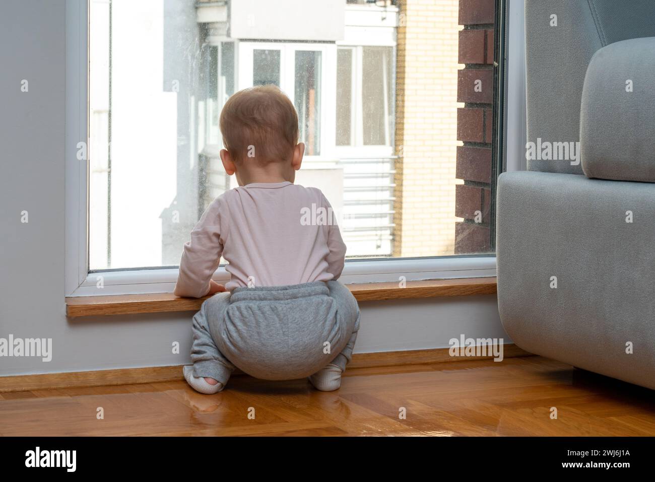 Baby waits by the window for dad to come home. Concept of family and longing Stock Photo