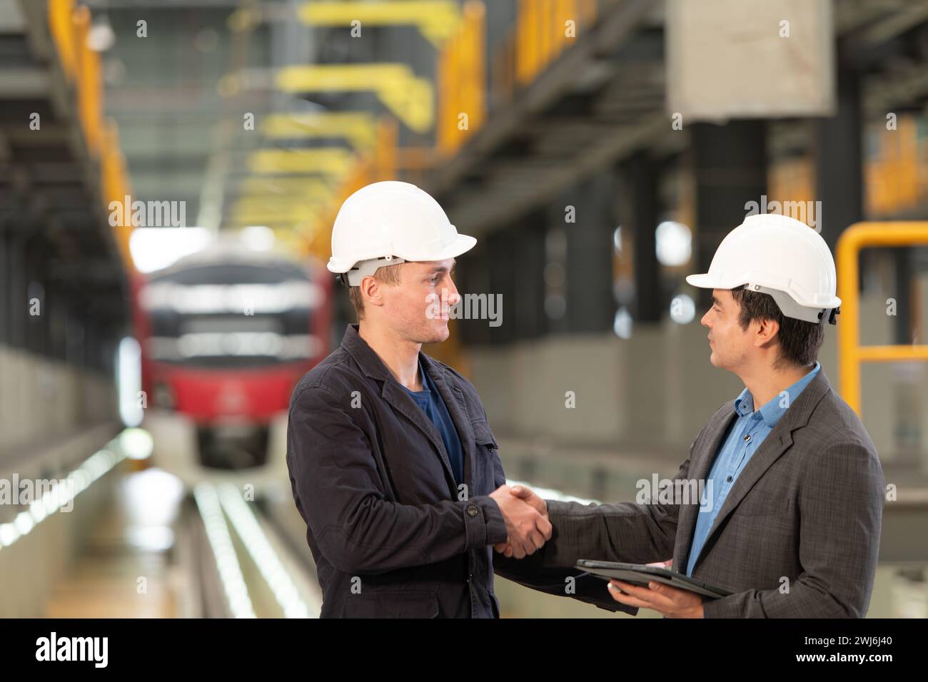 Two businessmen shaking hands after reaching an agreement to reserve equipment for use in repairing tracks and machinery of the Stock Photo