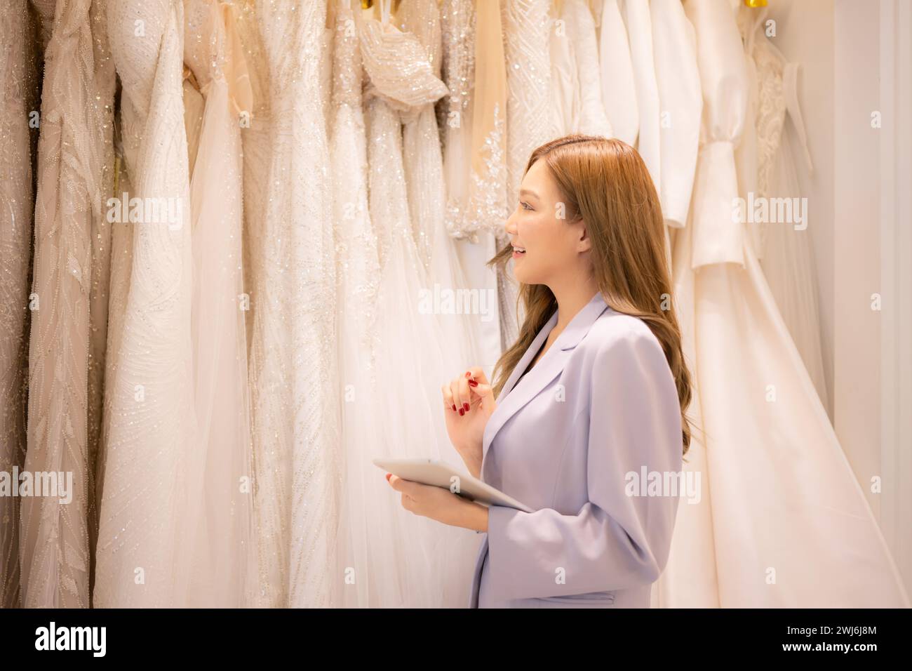 The shop owner is a designer and tailor. We are inspecting wedding dresses that are ready for the bride and groom to choose from Stock Photo