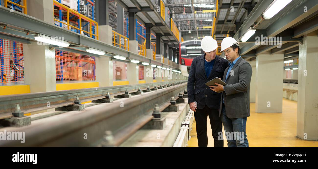 Two businessmen inspect rail work to reserve equipment for use in repairing tracks and machinery of the electric train transport Stock Photo