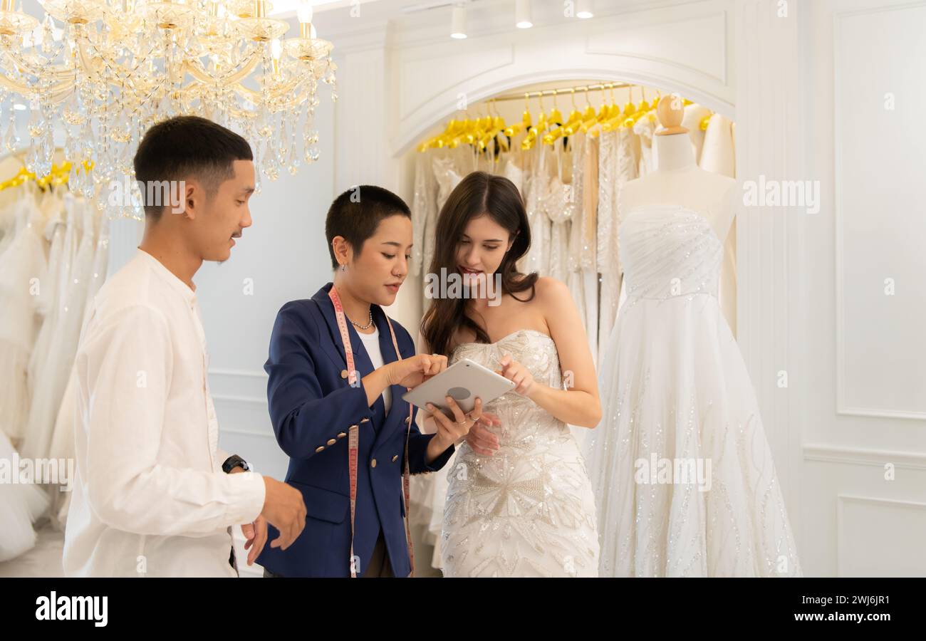 Bridal gown designers and tailors measure the size of the gown against the bride's figure when she comes to try on the gown in o Stock Photo