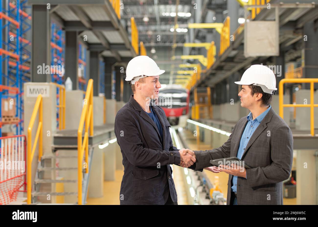 Two businessmen shaking hands after reaching an agreement to reserve equipment for use in repairing tracks and machinery of the Stock Photo