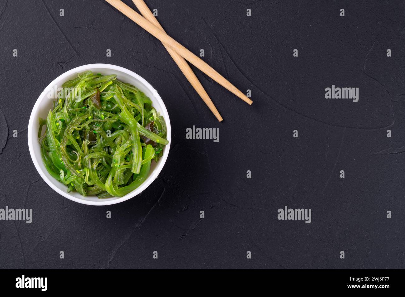 Chuka seaweed salad in a plate with chopsticks on a dark background Stock Photo