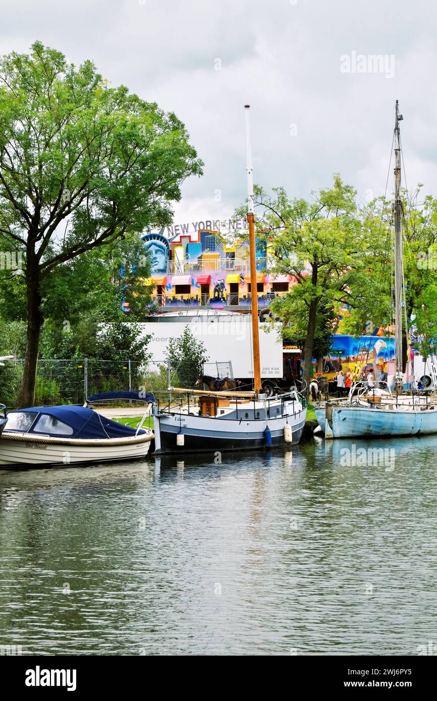 Boats are anchored in Nieuwe Haven, central Edam, with Kermis festivities going on in distance. Stock Photo